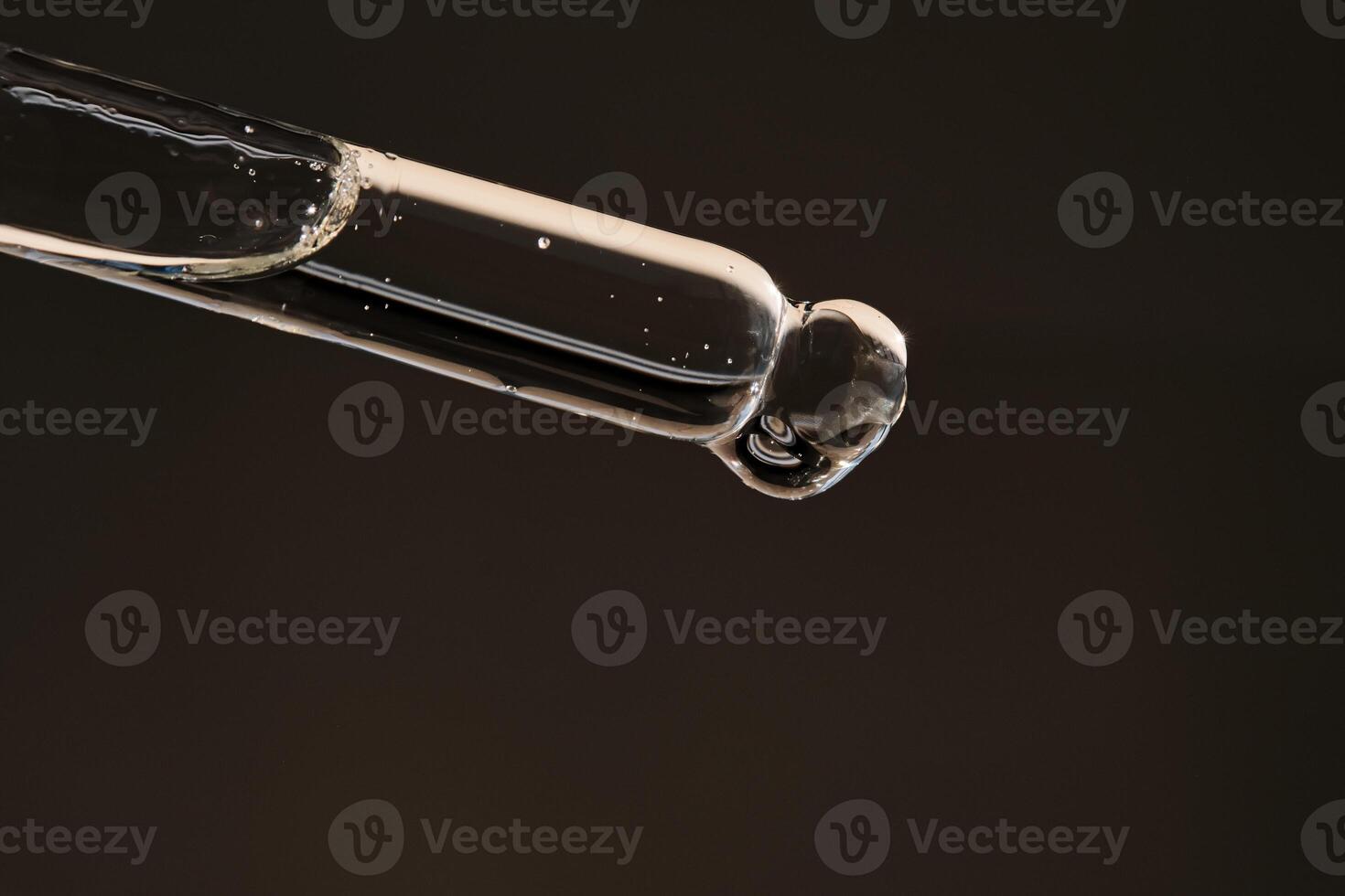 Pipette with serum on a dark beige background. photo