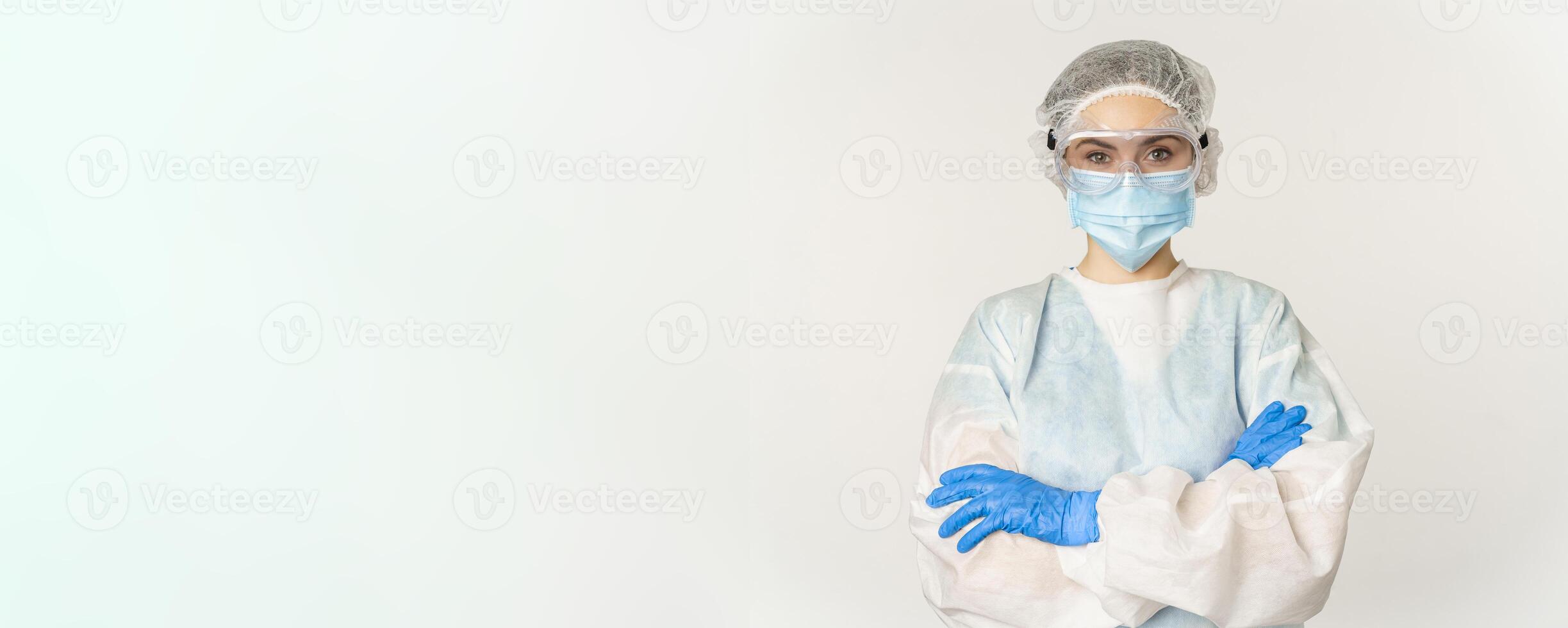 Professional doctor in personal protective equipment from coronavirus, cross arms on chest, looking confident, standing over white background photo