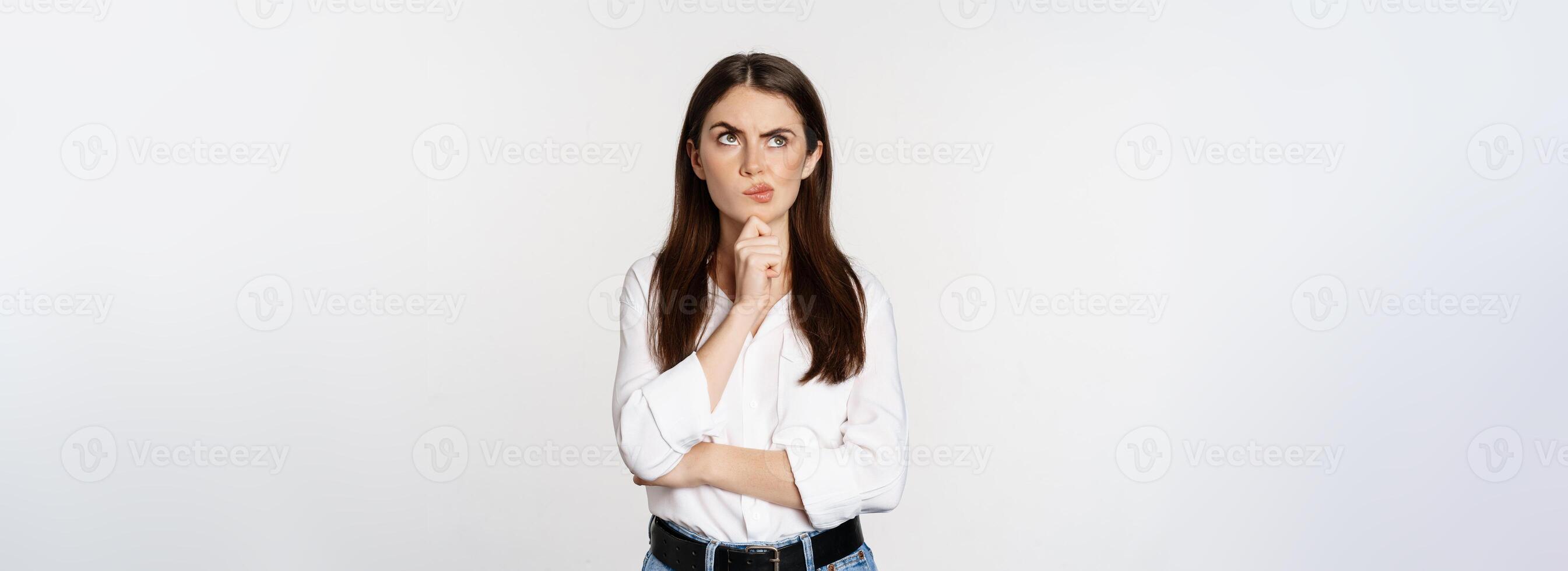 Portrait of female entrepreneur thinking, making choice, standing thoughtful, white studio background photo