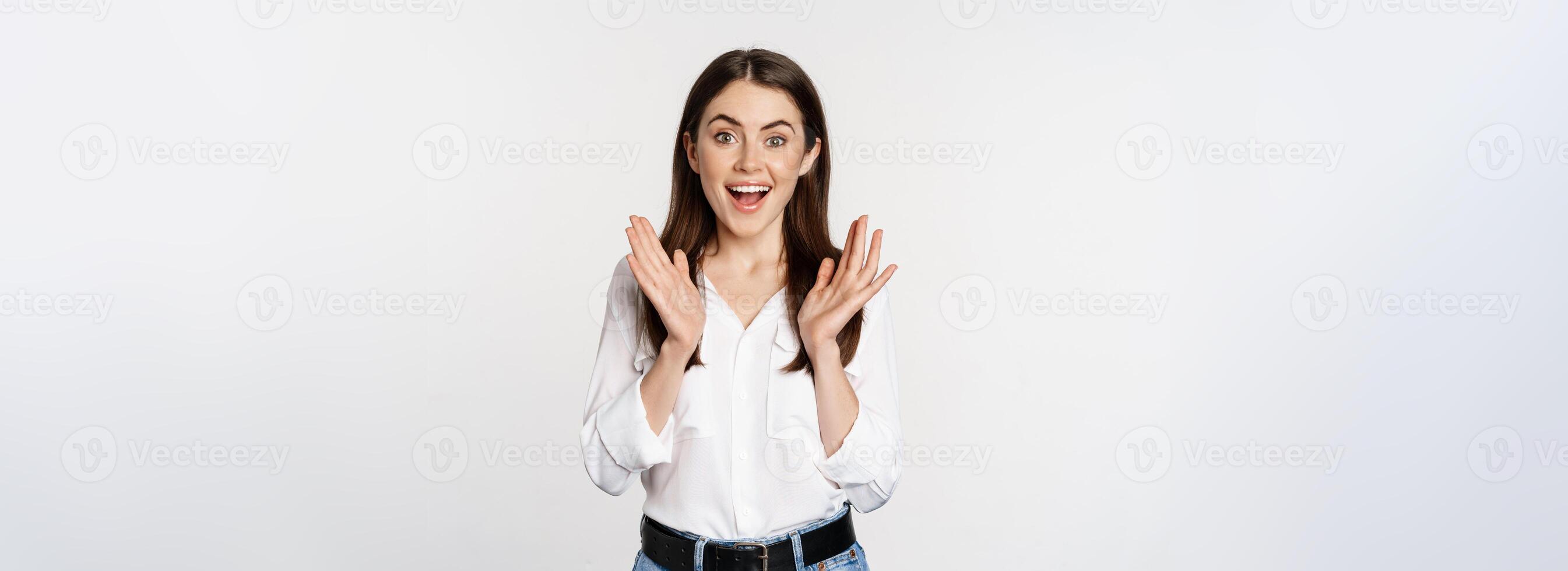 Enthusiastic laughing woman, smiling amused, clapping hands, applausing, standing in formal outfit over white background photo