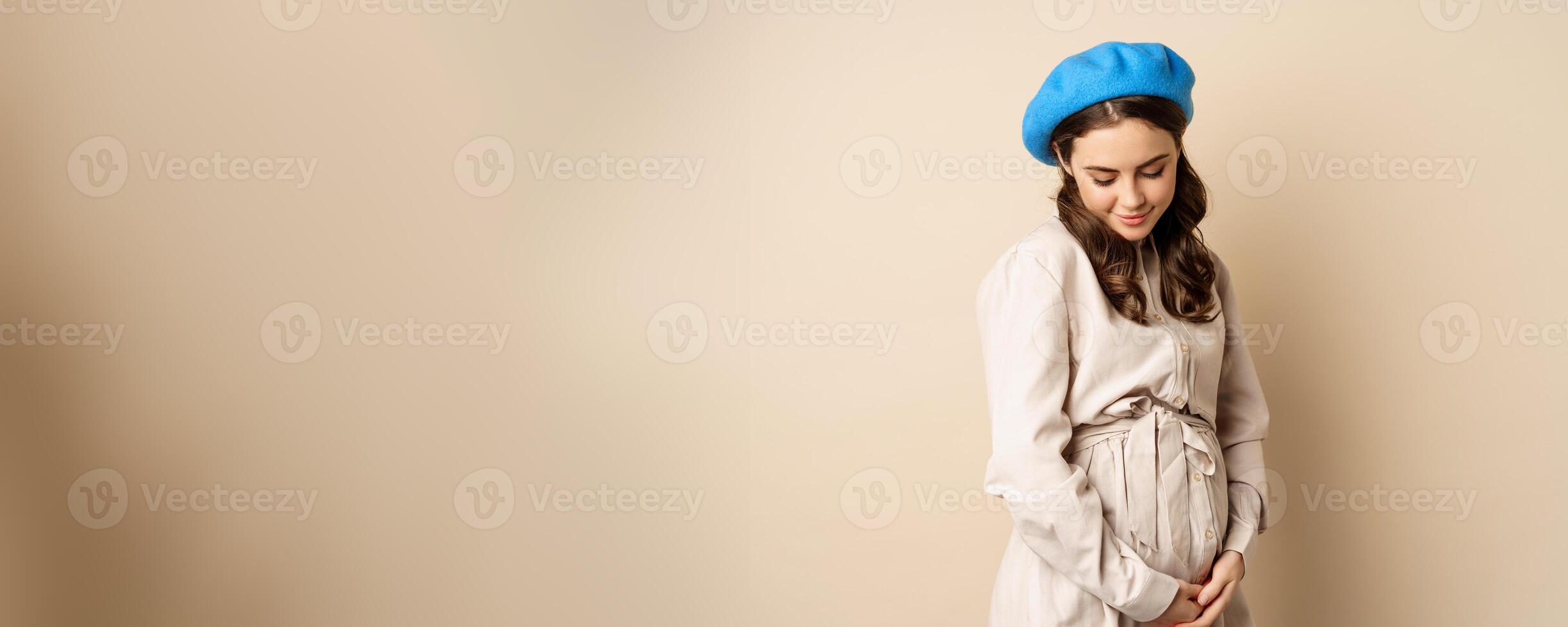 Pregnant woman. Young beautiful girl expecting baby, holding hands on belly and smiling tenderly, concept of surrogacy and pregnancy photo