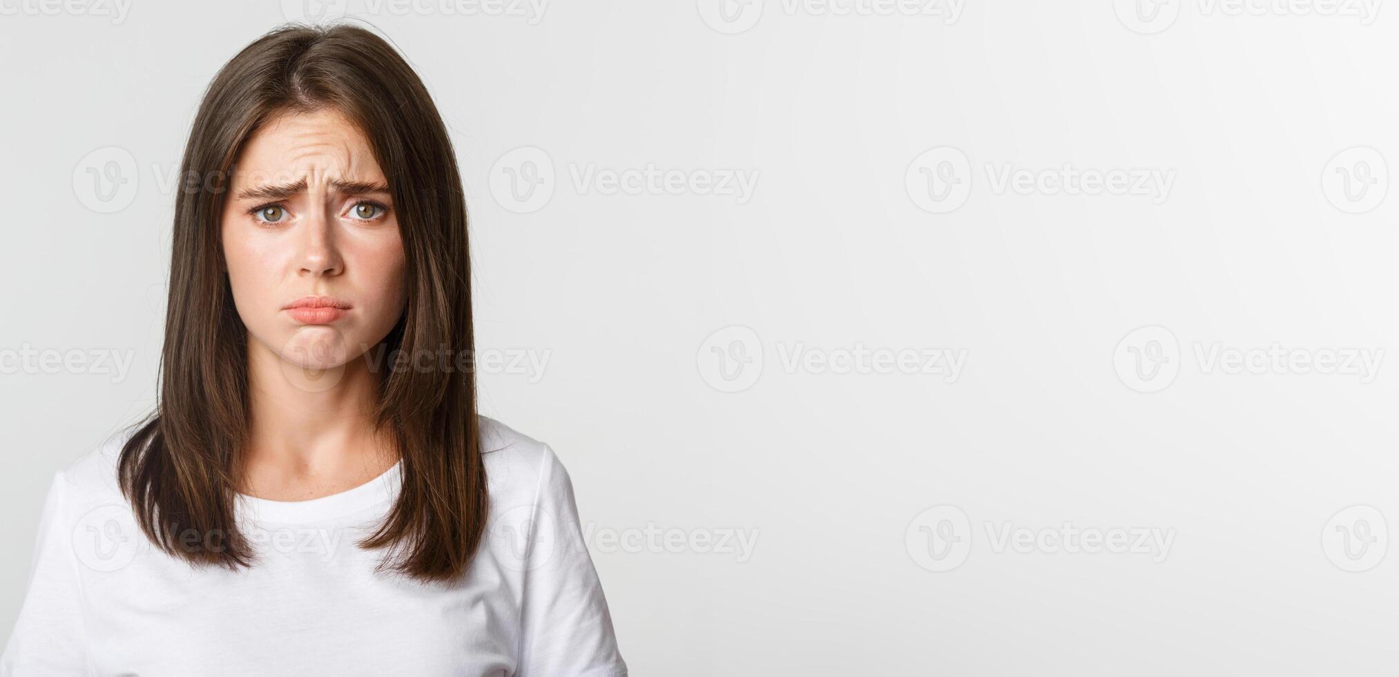 Close-up of upset and gloomy cute brunette girl sulking, looking miserable photo