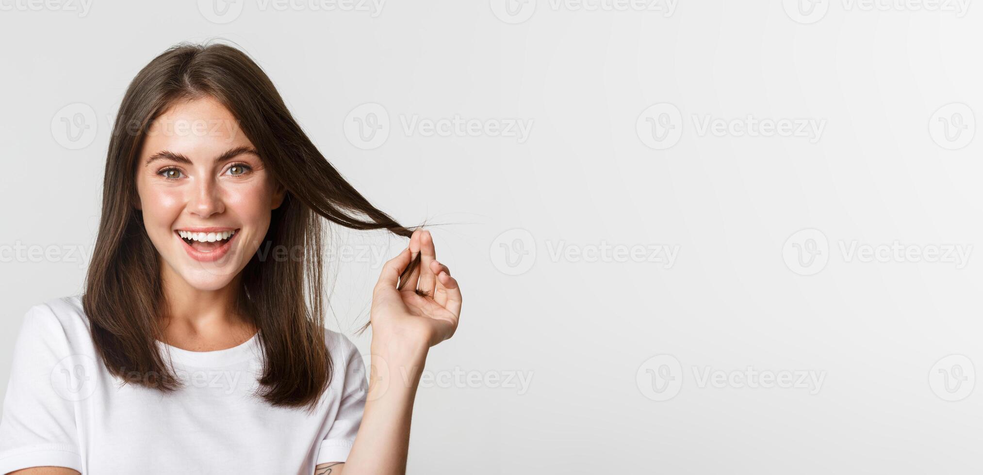 Portrait of flirty beautiful girl playing with hair and smiling at camera intrigued photo