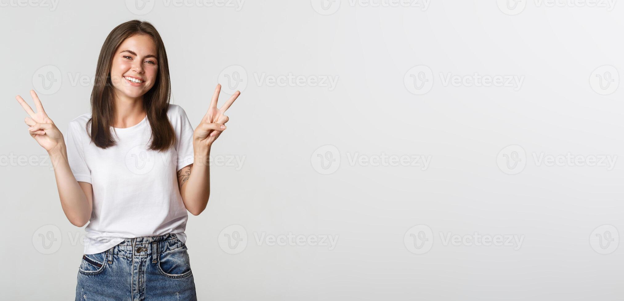 Cheerful attractive young woman smiling, showing peace gestures photo