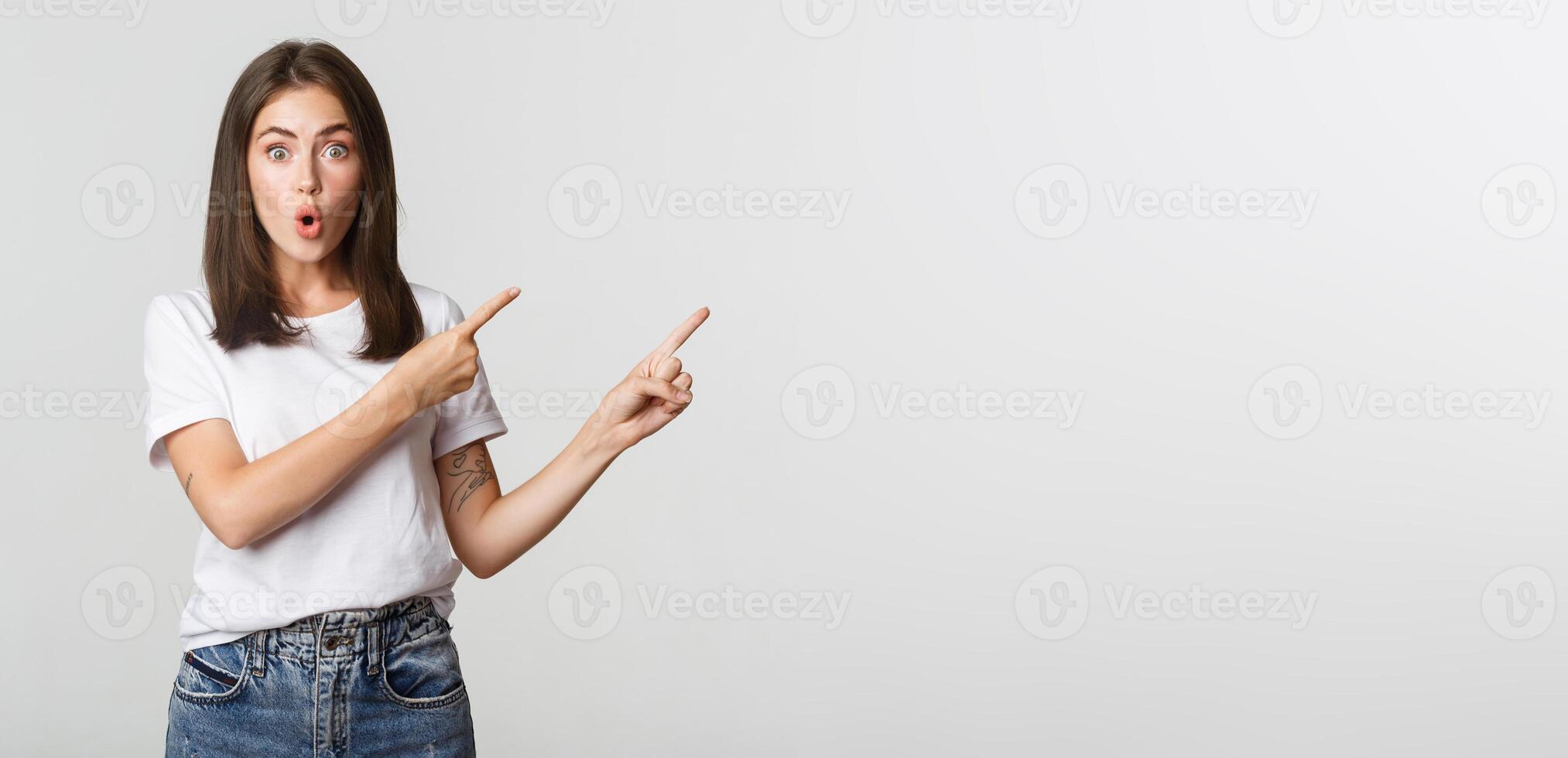 Impressed and amused brunette girl say wow and pointing upper right corner at banner photo