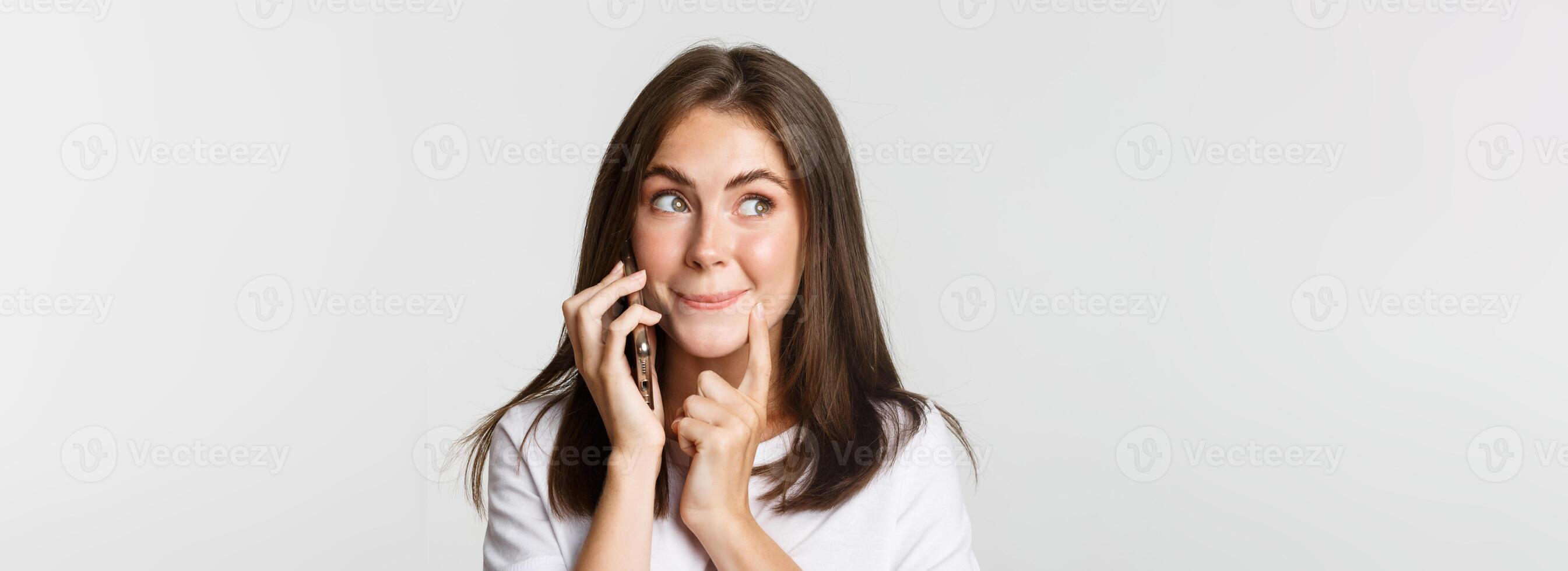 Close-up of intrigued cute girl talking on phone, looking interested photo