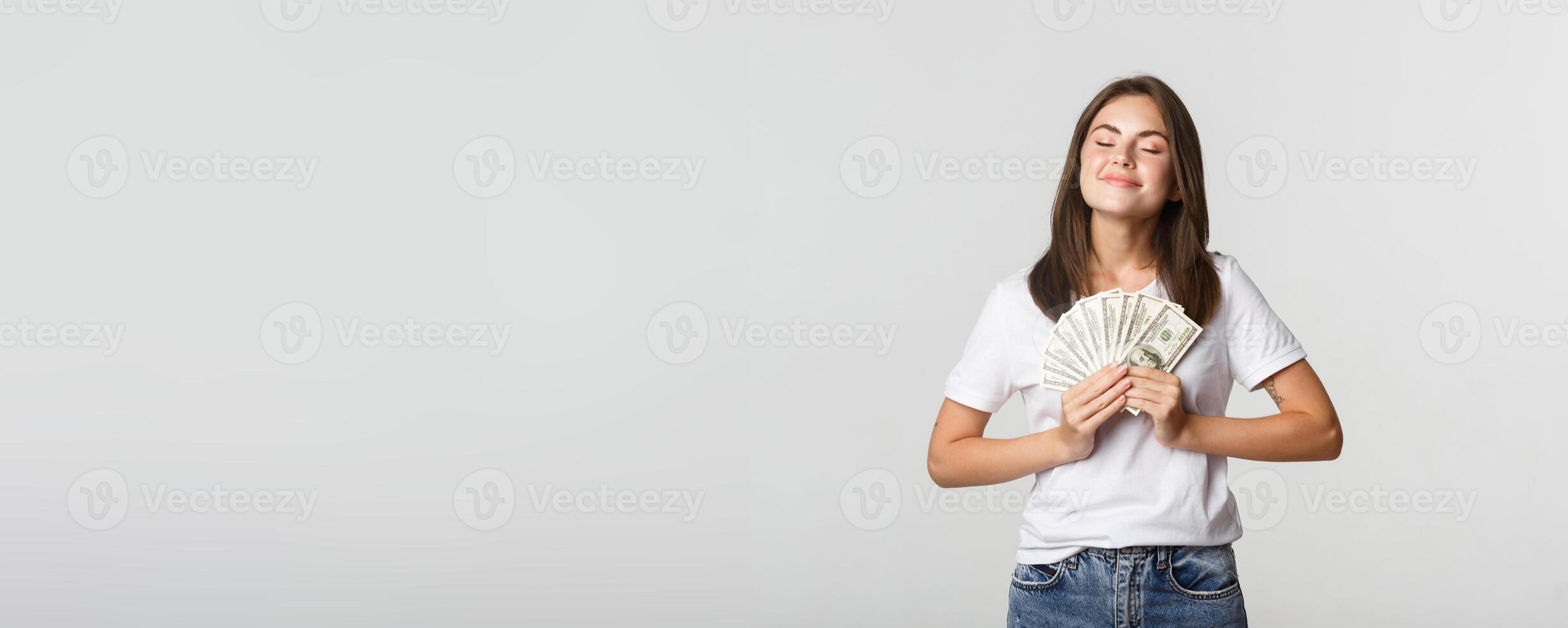 Happy and satisfied smiling woman close eyes and enjoying having money photo