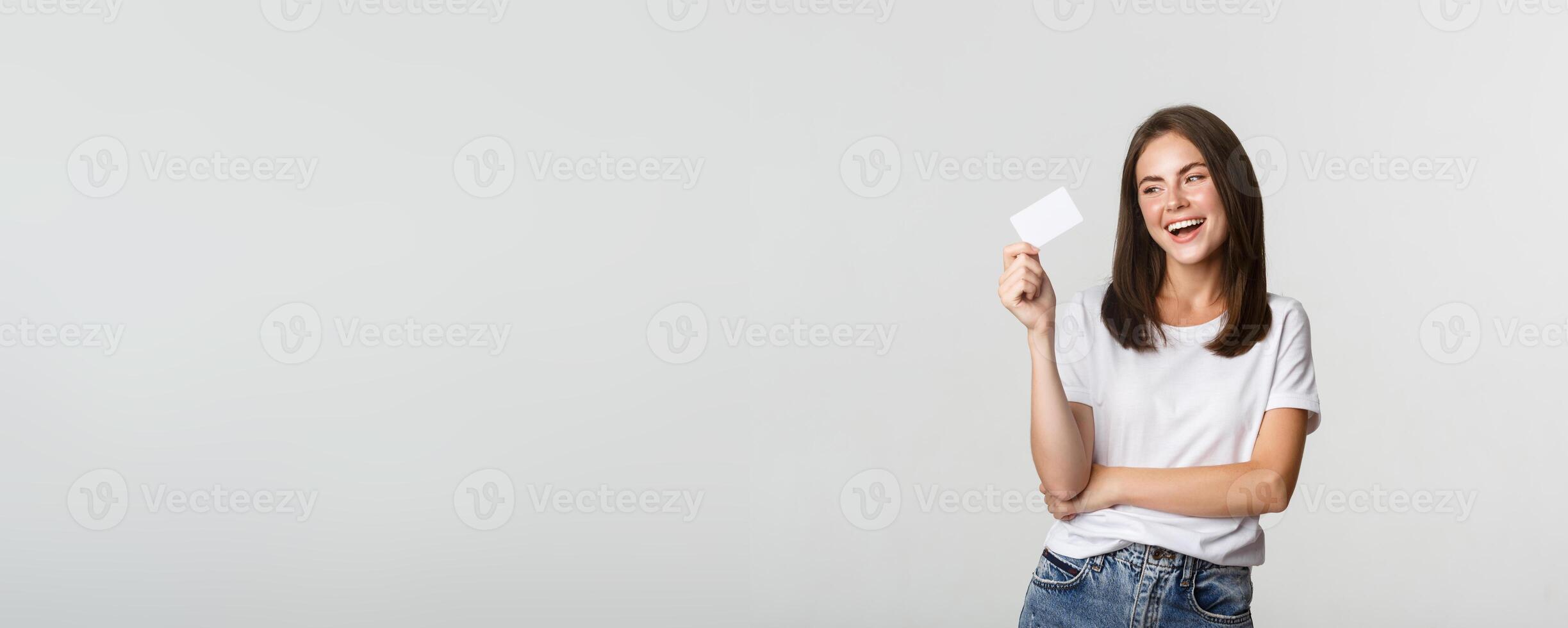 Attractive happy brunette girl laughing and holding credit card, white background photo