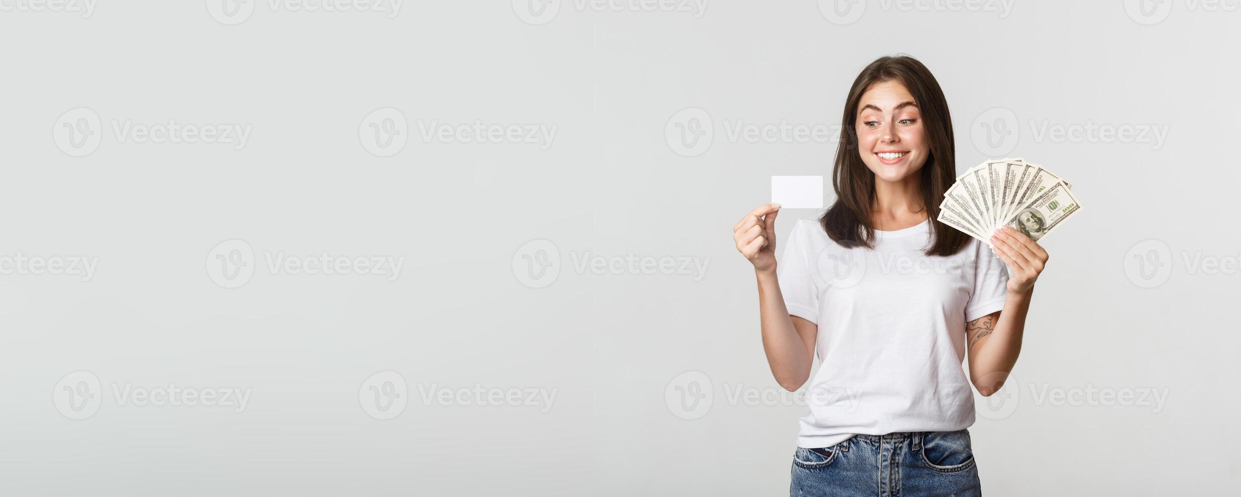 Portrait of excited smiling girl holding money and credit card, white background photo