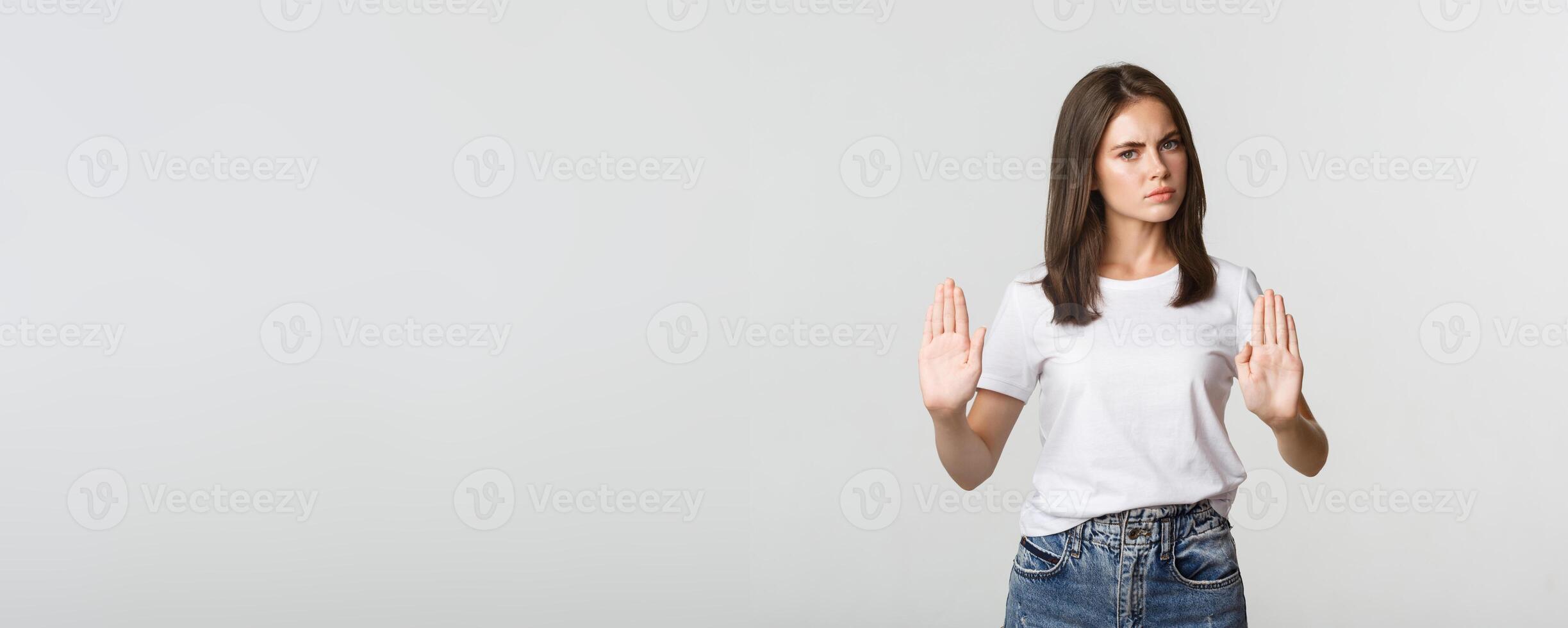 Serious displeased young woman showing stop gesture, saying no photo