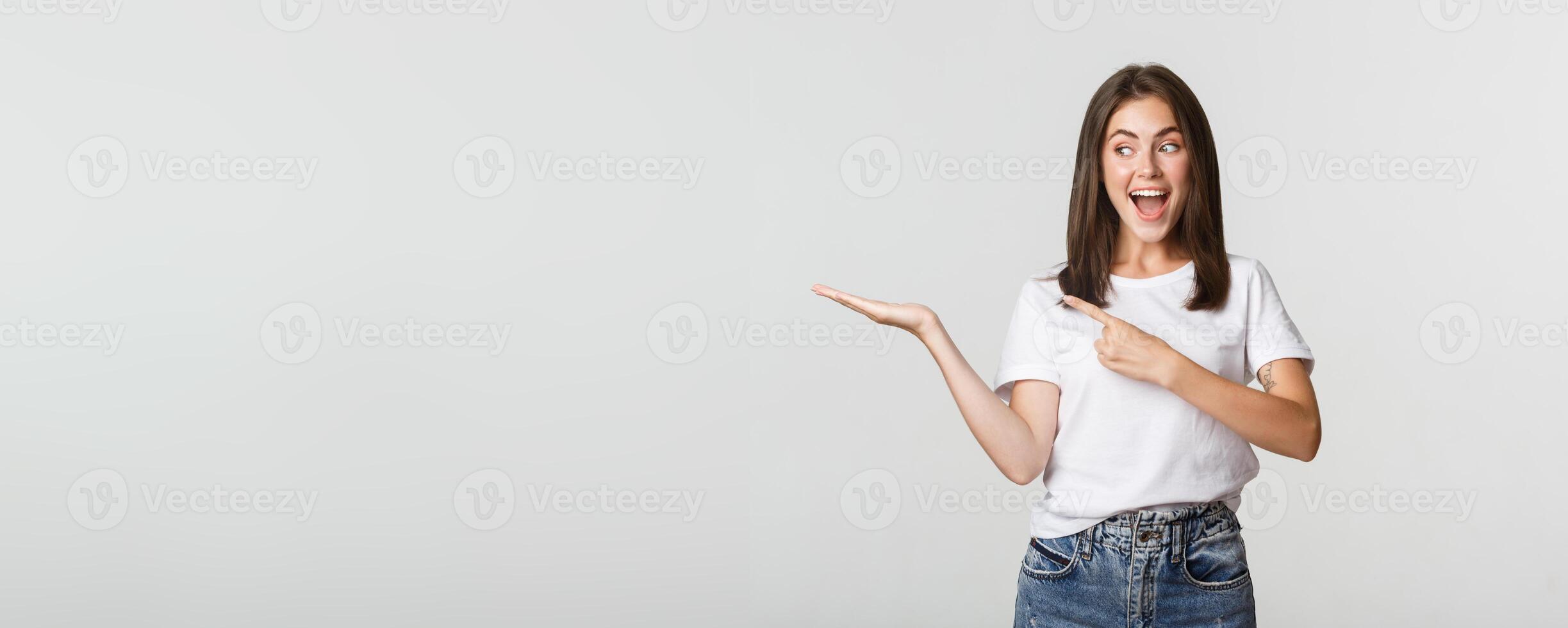 Attractive young woman pointing finger at something she holding on hand photo