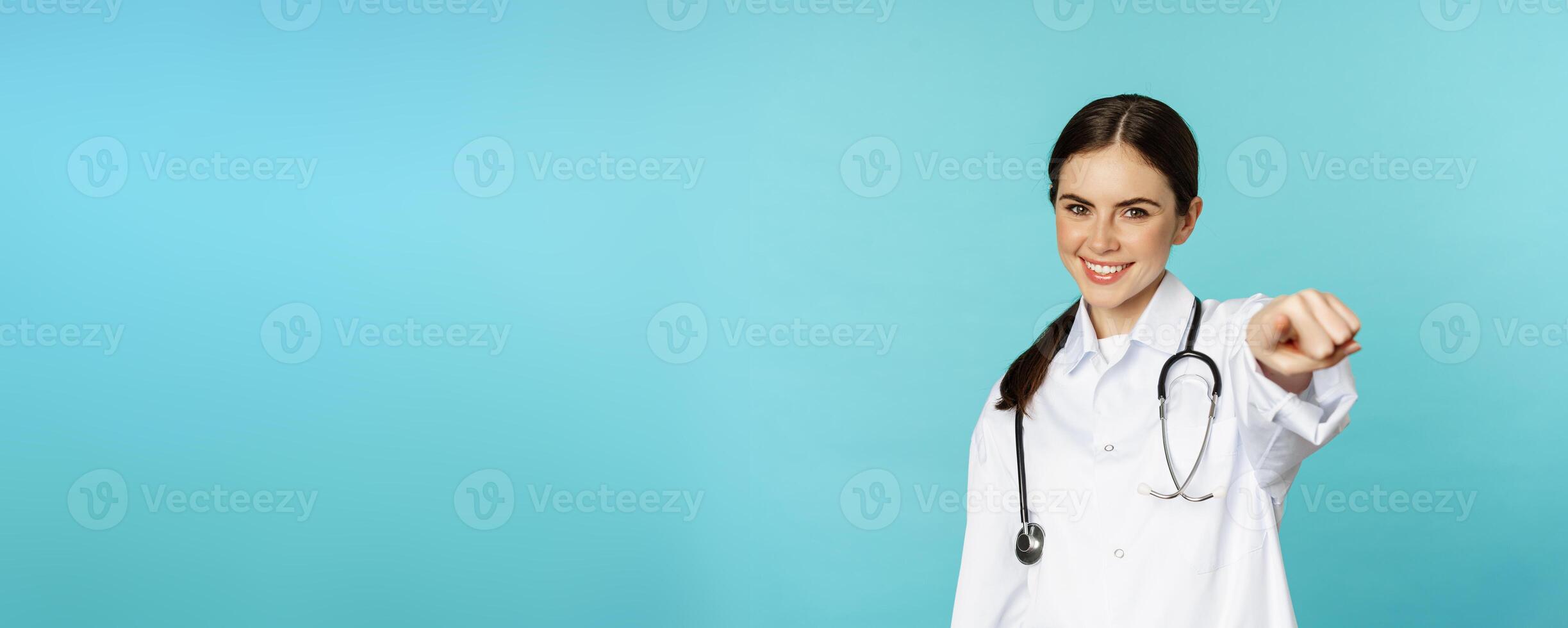 Young professional woman doctor, medical worker showing okay, ok zero gesture and smiling satisfied, recommending, complimenting smth, torquoise background photo