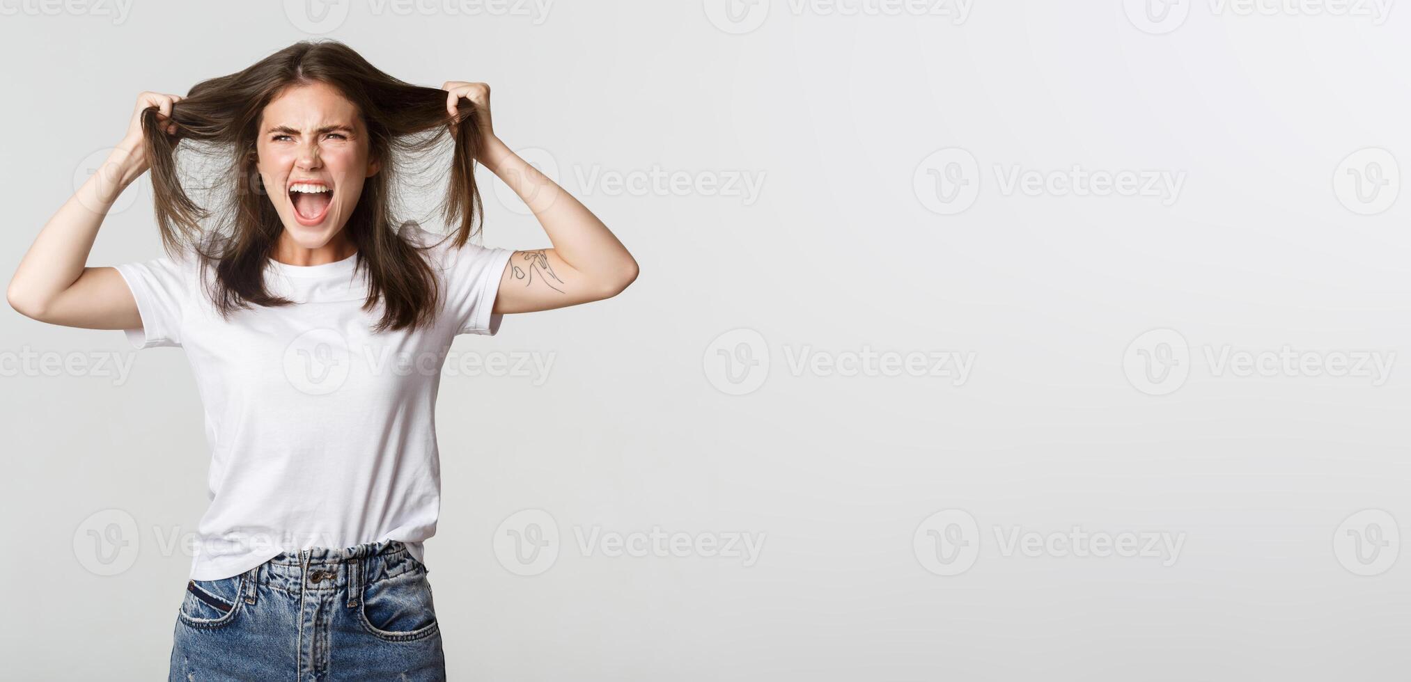 Outraged mad young woman ripping hair on head and yelling angry photo