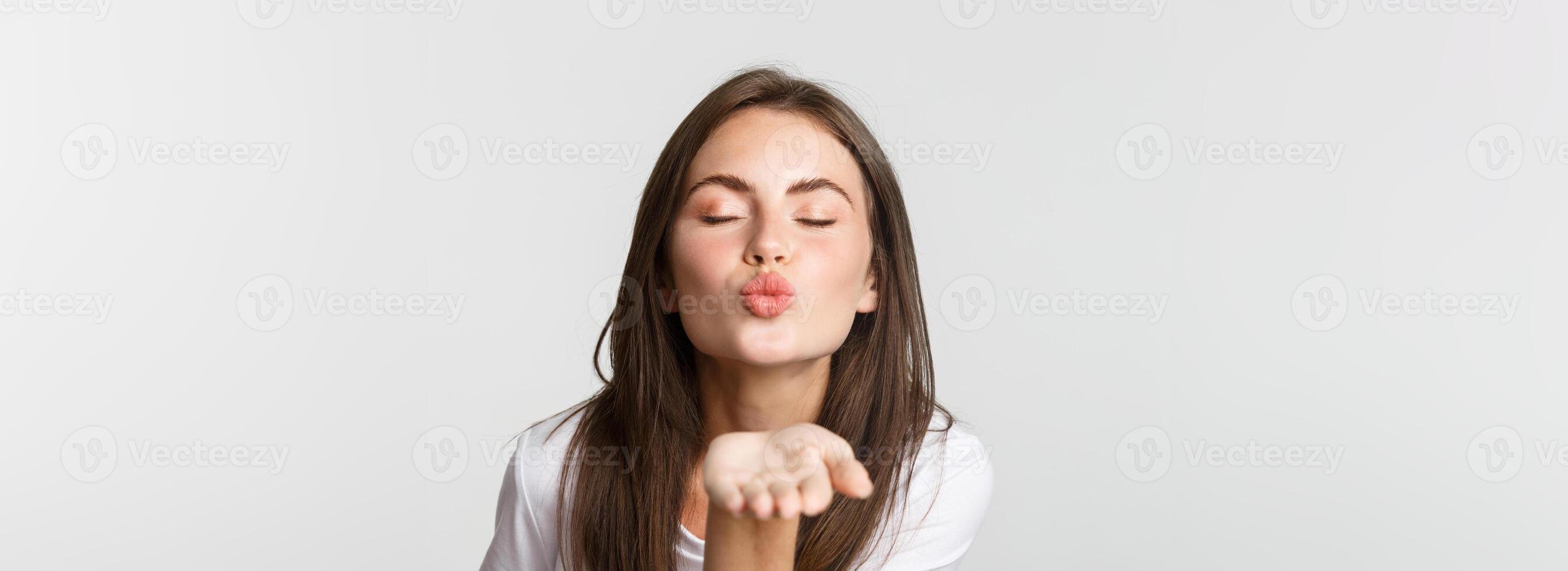 Close-up of beautiful flirty girl pouting lips and sending air kiss at camera photo