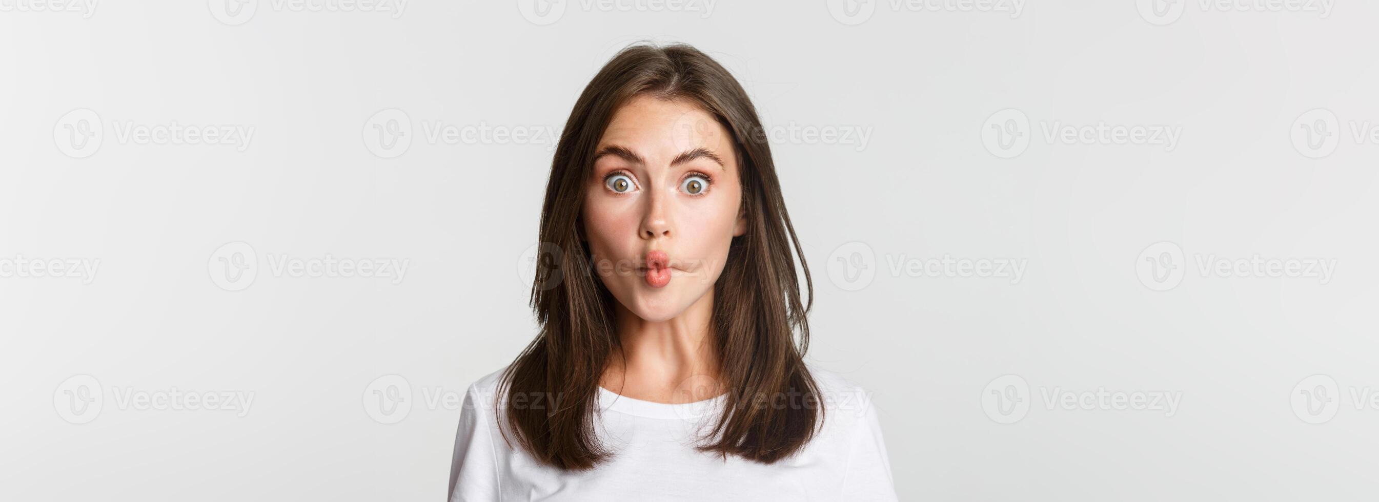 Close-up of funny and cute brunette girl suckink lips, making fish grimace, white background photo
