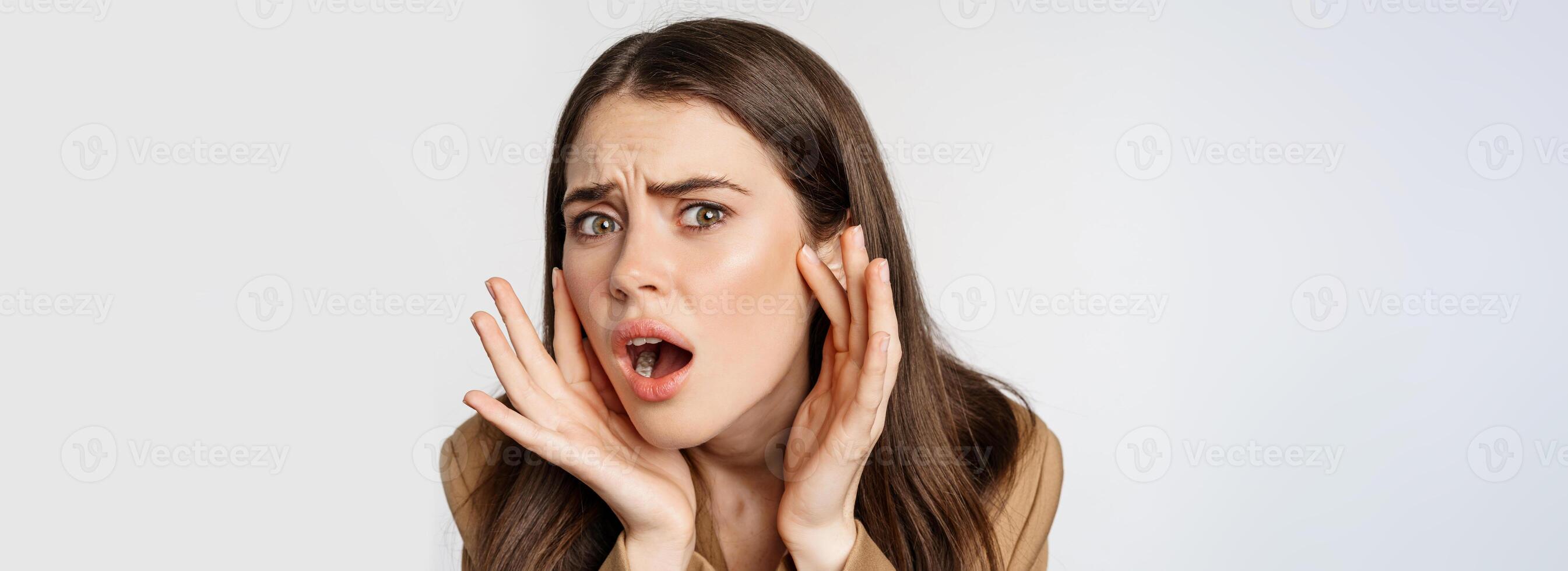 Image of sad girl looking in mirror and touching facial skin, shocked and frustrated over bad skin condition, standing over white background photo