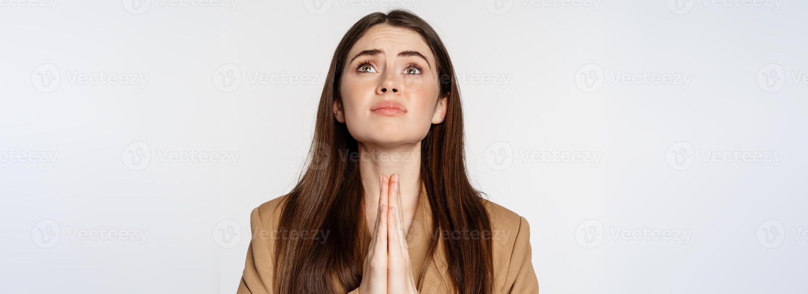 Hopeful corporate woman, student praying, begging god, looking up and pleading, standing over white background photo