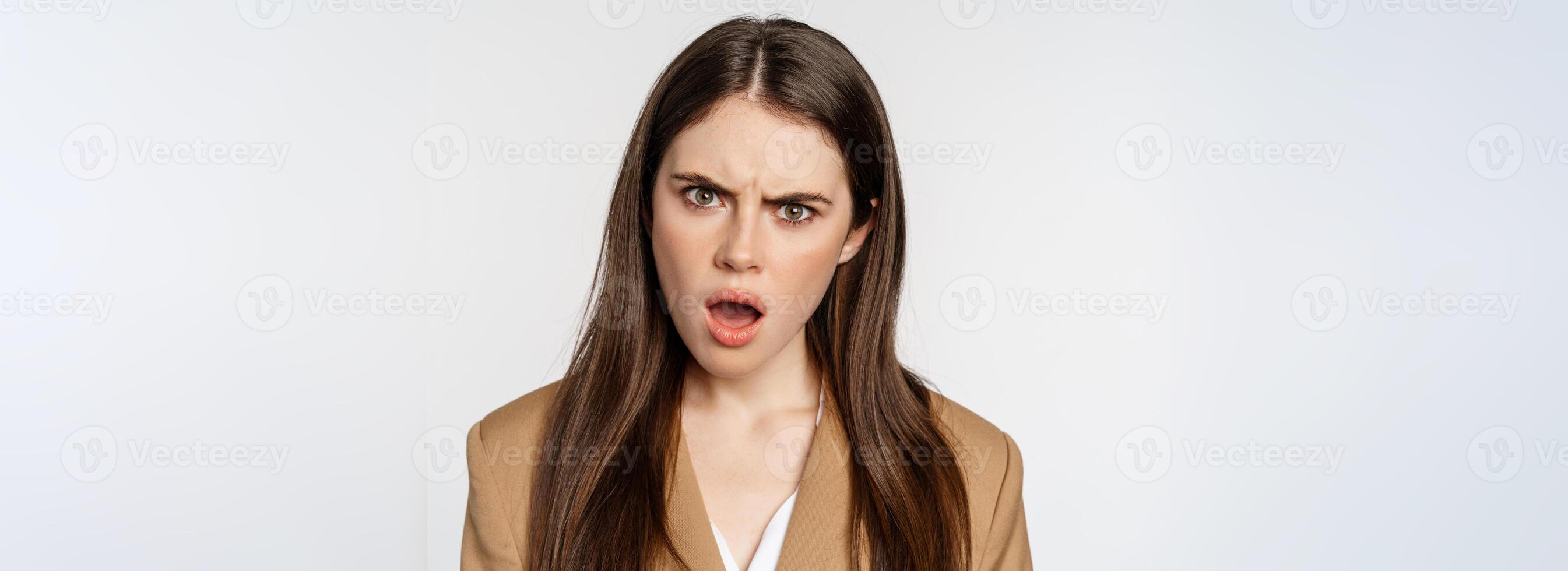 Confused office worker, businesswoman staring shocked and insulted at camera, standing over white background photo