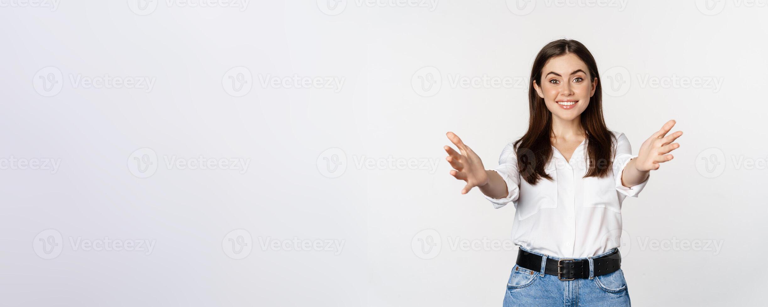 Enthusiastic laughing woman, smiling and stretching out arms forward, welcome you, greeting, standing over white background photo