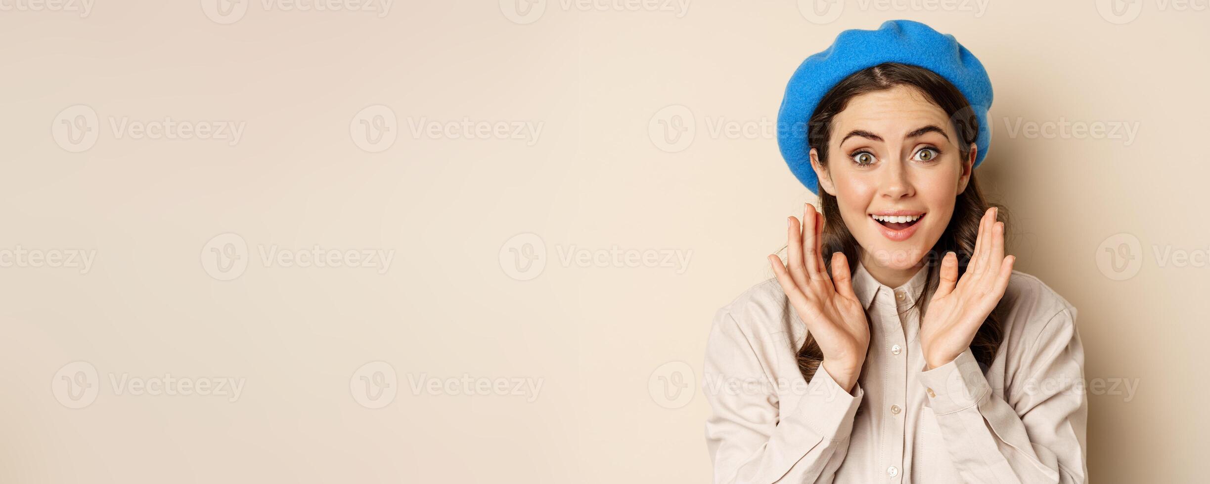 Close up portrait of woman looking surprised, amazed reaction at big news, special deal, standing over beige background photo