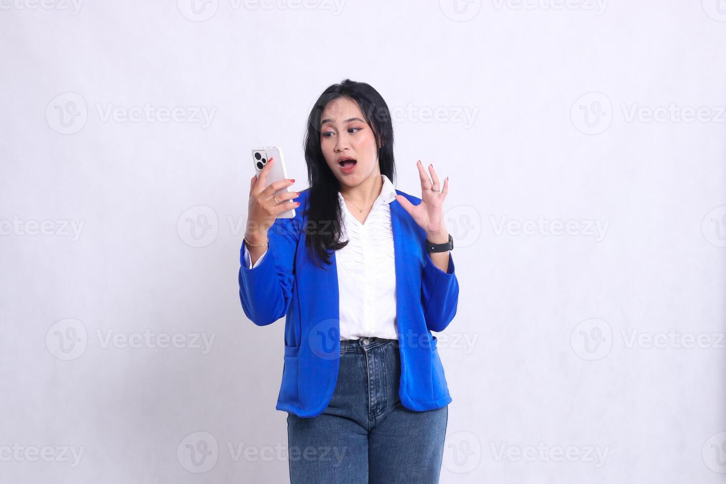 beautiful young office woman wearing blue formal suit standing shocked candid operating smartphone handphone while her hand sideways away from cellphone. for technology , lifestyle, mobile transaction photo