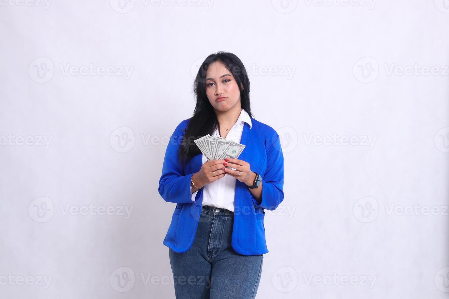 beautiful adult office girl wearing blue formal suit standing pouting to camera both hands holding dollar bills isolated white background. for transaction, finance, business content photo