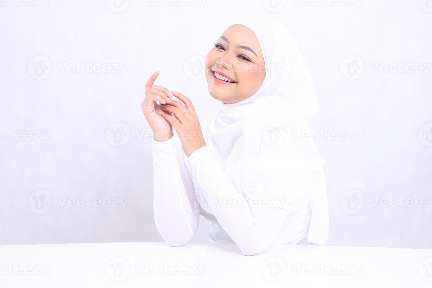 The charm of a veiled woman laughing at the camera with radiant white skin, glowing and healthy, both hands sticking to the right side isolated on a white background. Closeup face with makeup photo