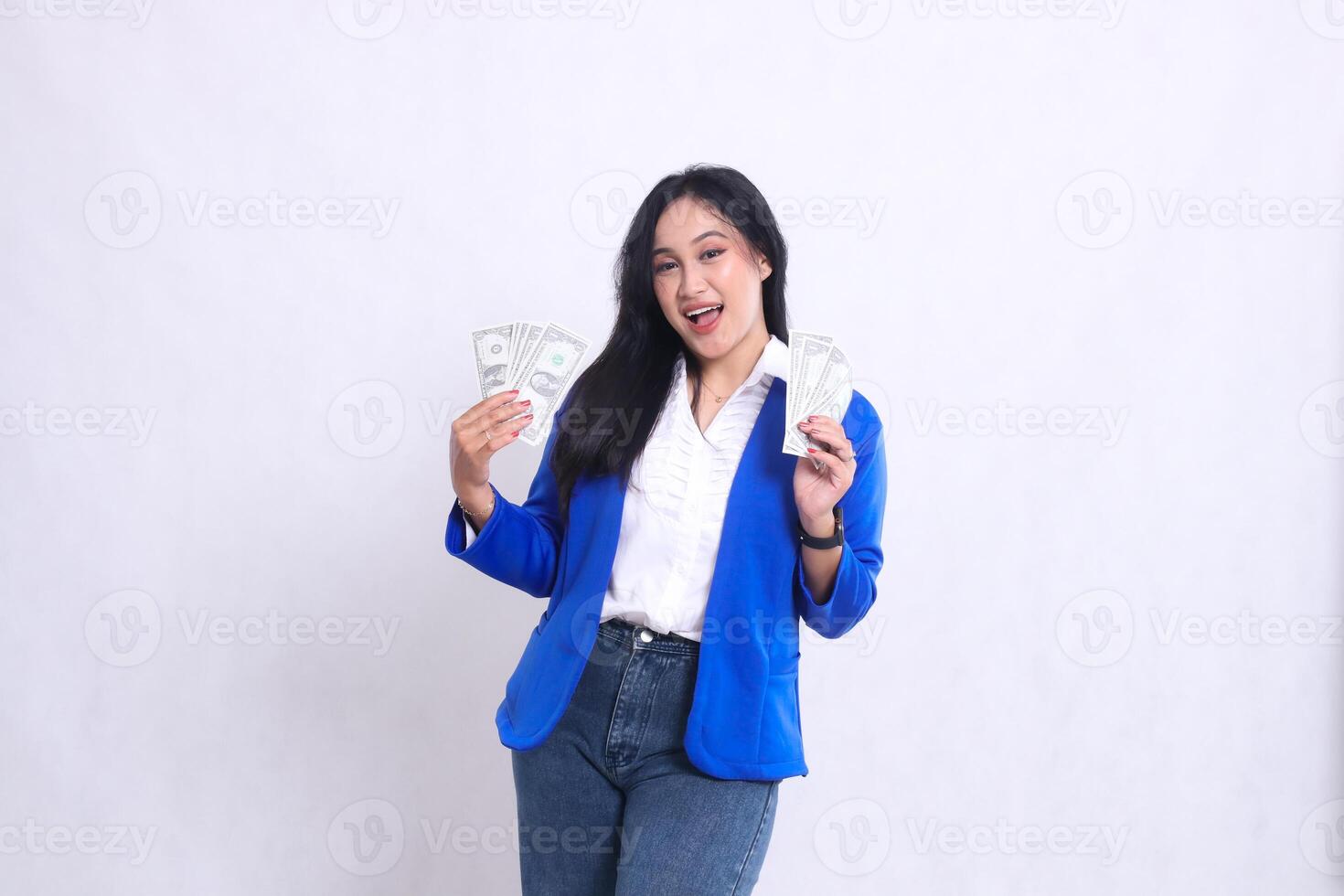 beautiful adult office woman wearing blue formal suit standing cheerfully to the camera holding dollar bills to the right and left isolated on white background. for transaction, finance, business photo