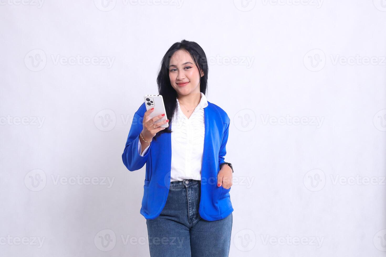 The charm of a beautiful young office woman wearing a blue formal suit standing smiling at the camera operating a smartphone while putting it in her suit pocket. for technology, mobile transactions photo
