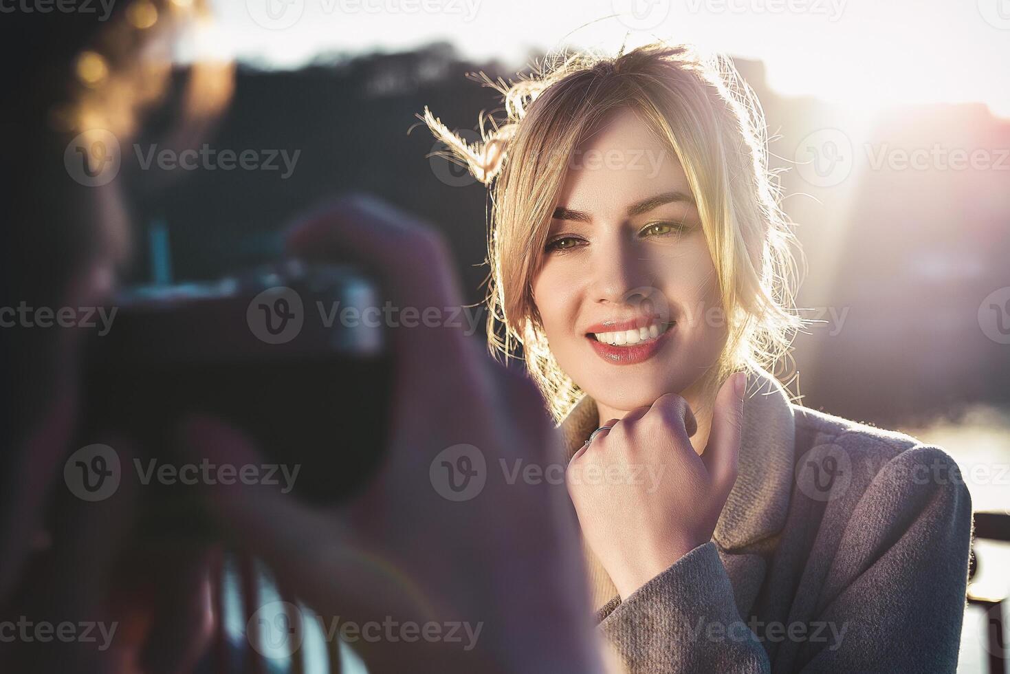 A man make a portrait of happy smiling woman standing on the bridge on sunny summer or spring day outdoor photo