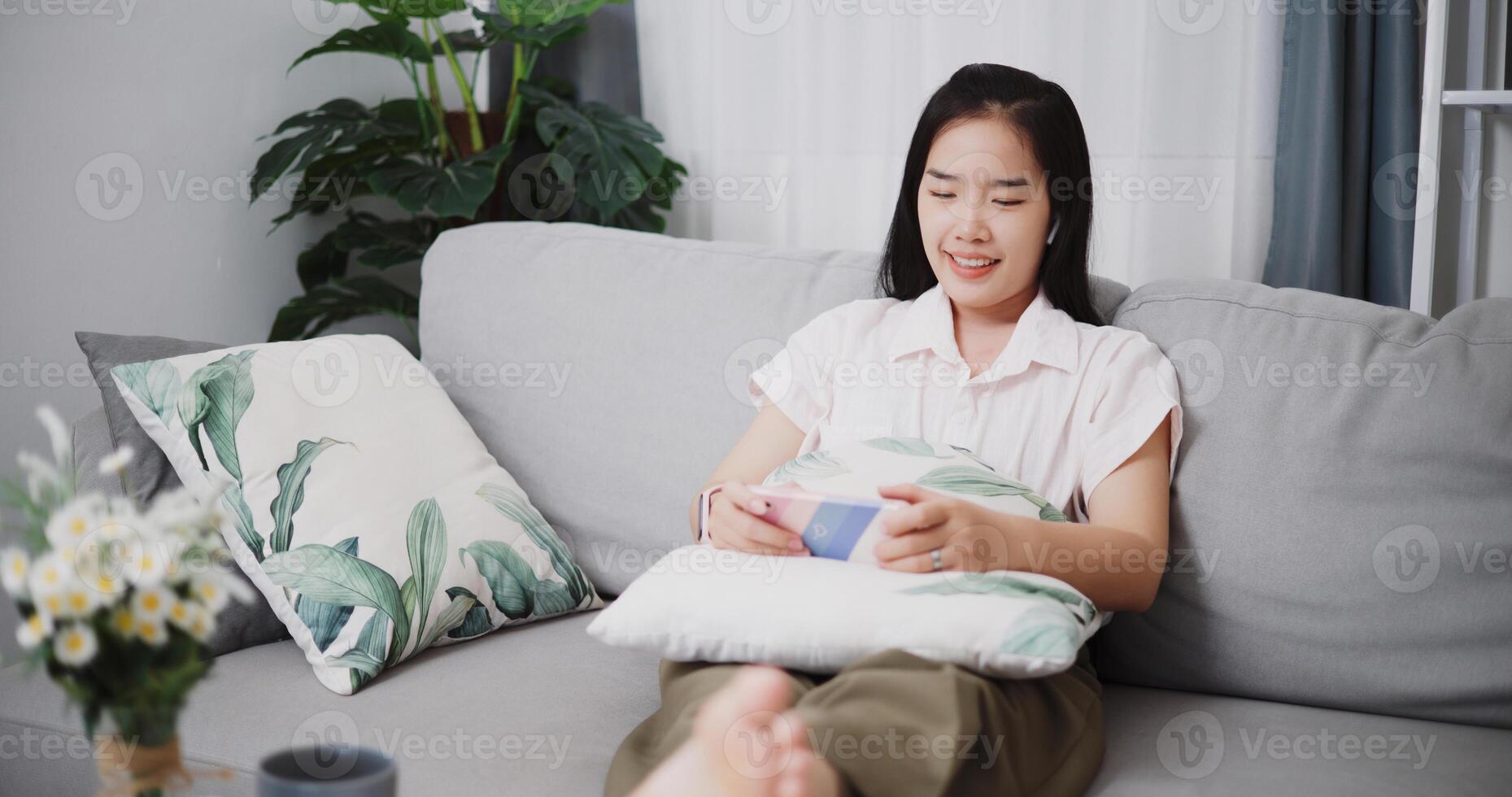 High angle view, Carefree young women wear wireless headphone play game online with smartphone on sofa at home ,Lifestyle with device technology photo