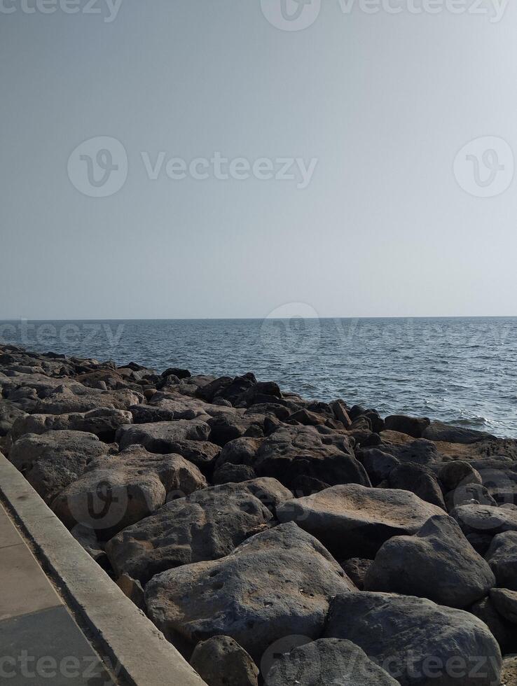 a man walking on the beach with a skateboard photo