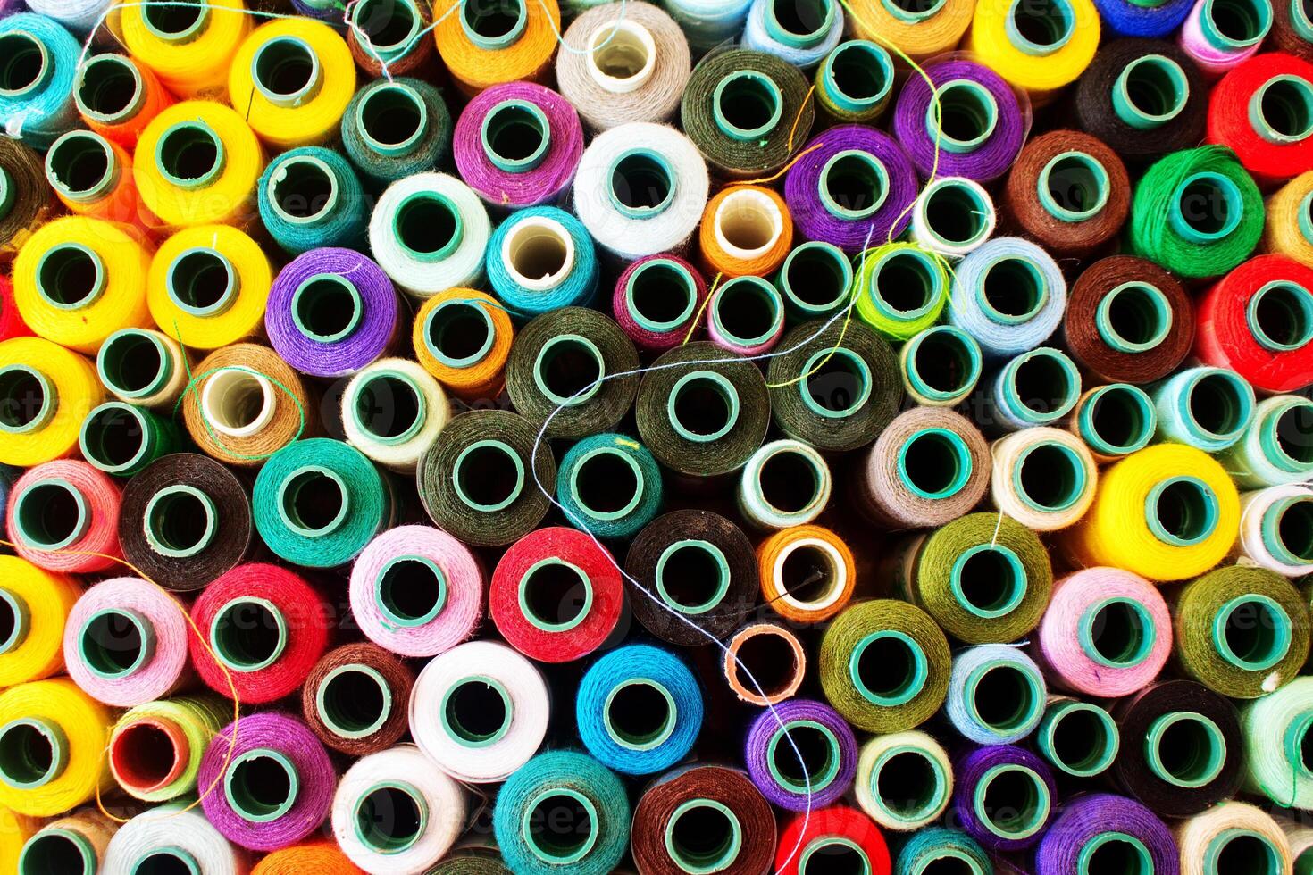 Top view of a vibrant collection of various colored thread spools. photo