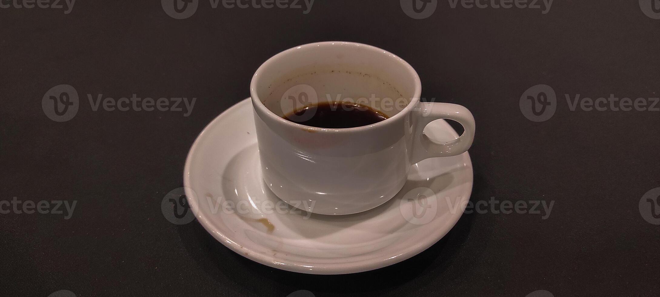 White coffee in mug with saucer on black background photo