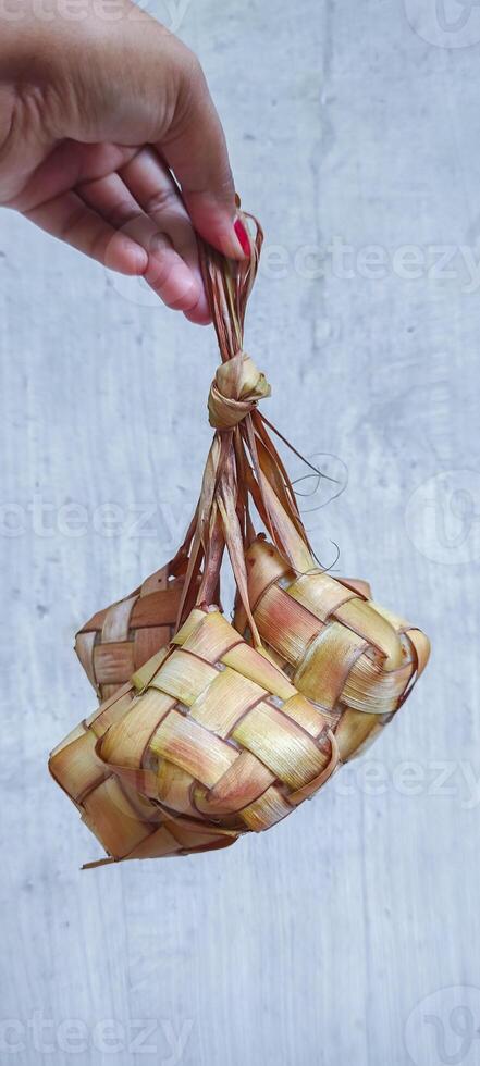 woman held cooked ketupat or South East Asian rice cakes bundle, dish during Eid Mubarak celebratory in Indonesia and Malaysia photo