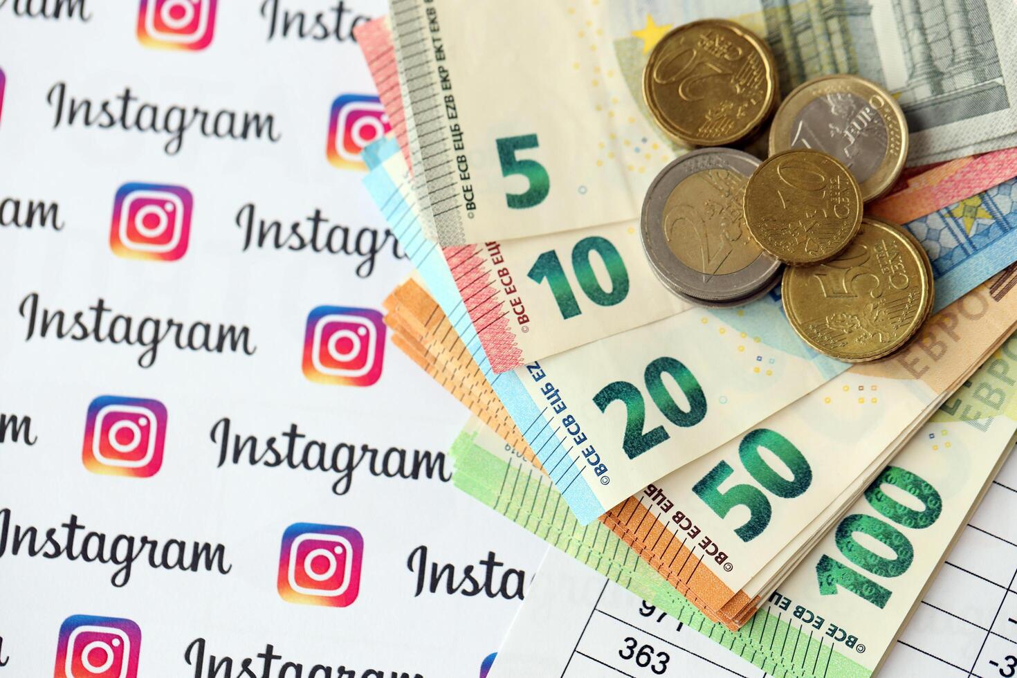 KYIV, UKRAINE - APRIL 20, 2024 Instagram logo and many euro money bills. Symbol of famous social network platform and european currency banknotes photo