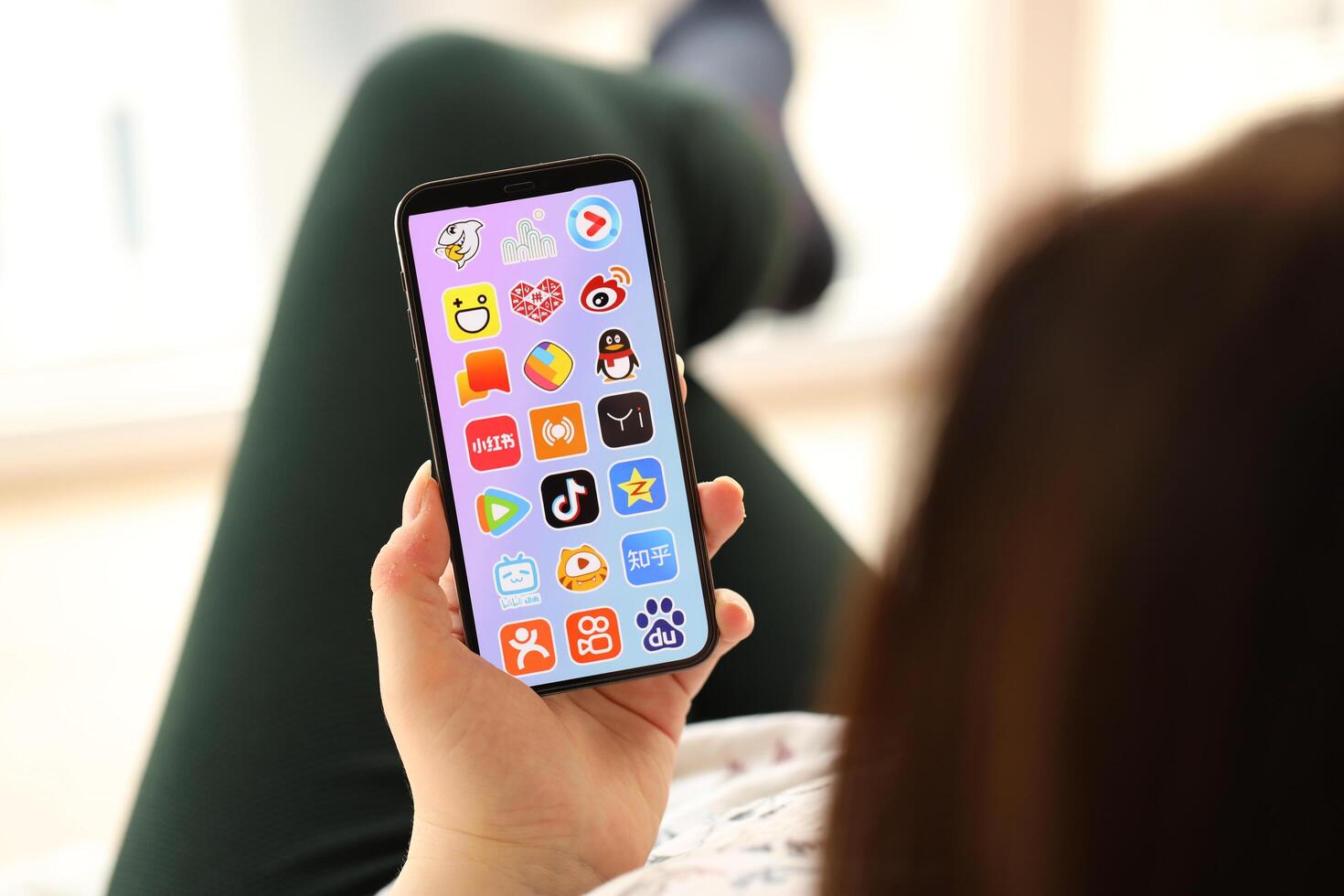 KYIV, UKRAINE - APRIL 1, 2024 Asian apps icon on smartphone screen in young female hands photo