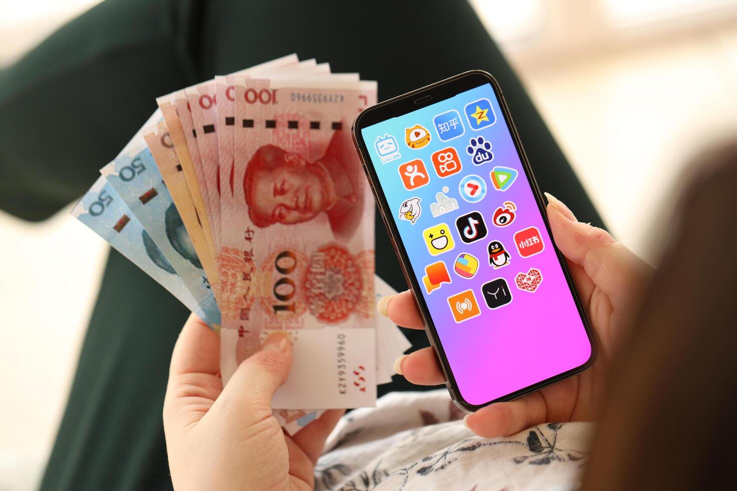 KYIV, UKRAINE - APRIL 1, 2024 Asian apps icon on smartphone screen and money in female hand photo