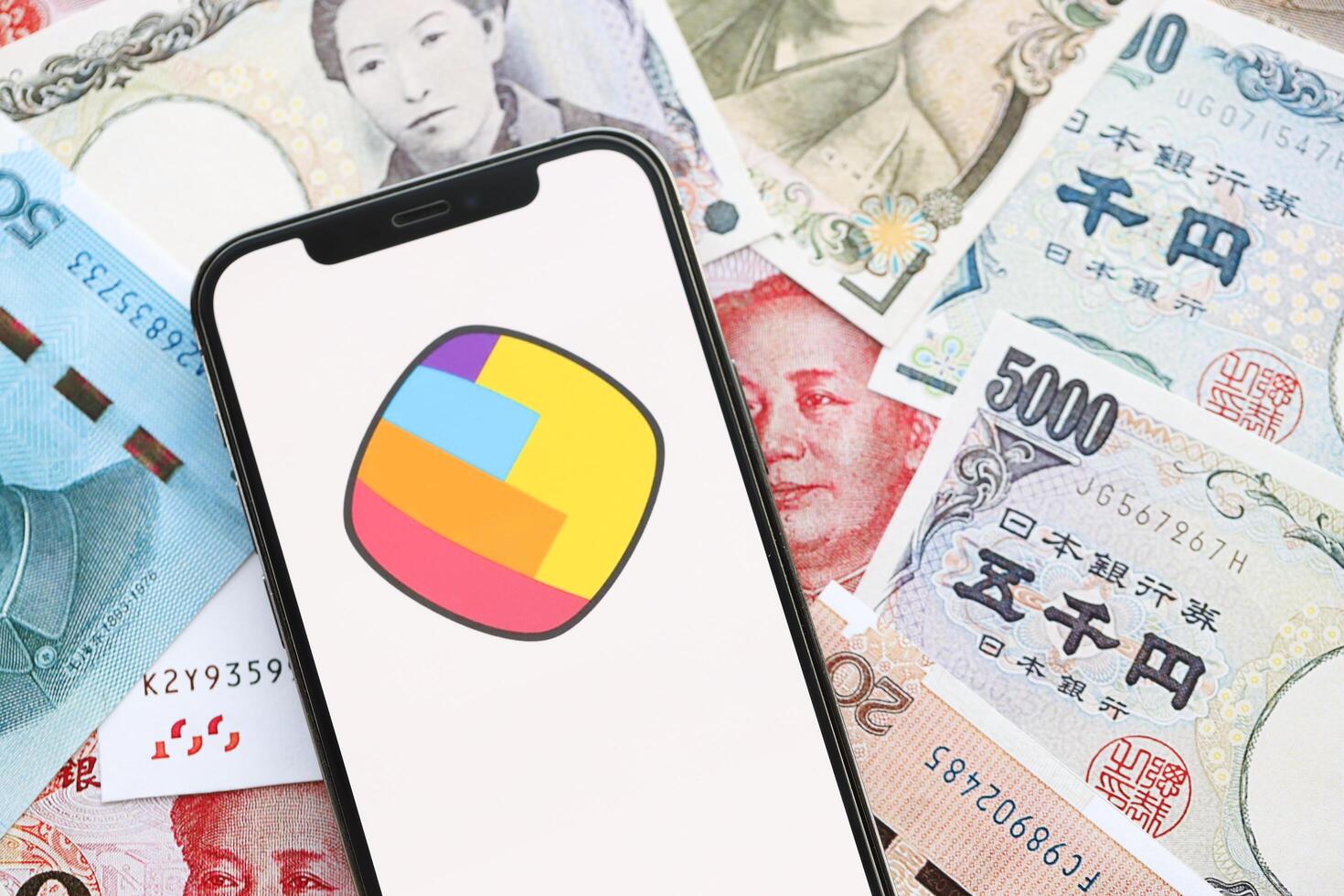 KYIV, UKRAINE - APRIL 1, 2024 Sharechat icon on smartphone screen on many asian money bills photo