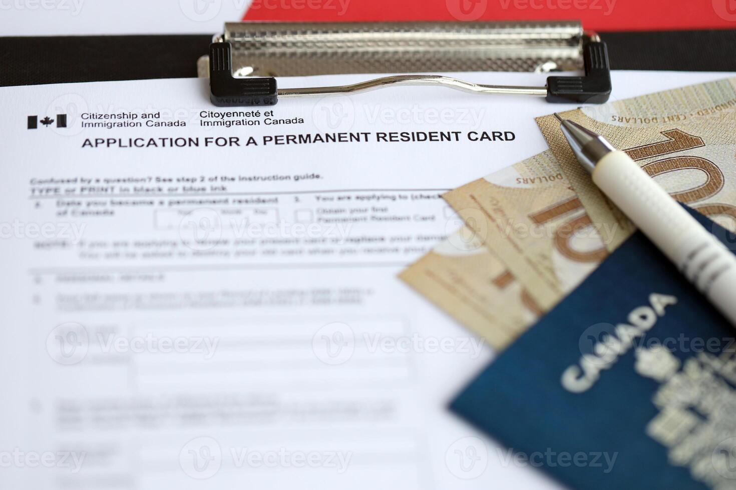 Application for permanent resident card on table with pen and canadian passport with money photo