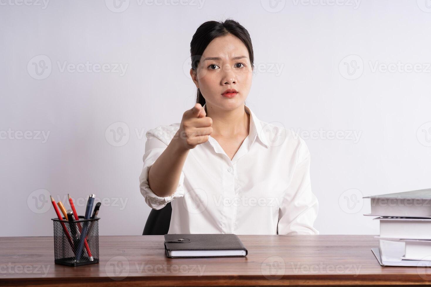 Young female businessman sitting at desk on white background photo