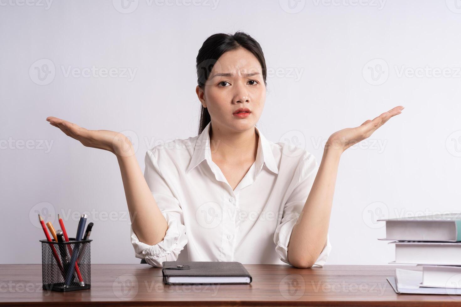 Young female businessman sitting at desk on white background photo