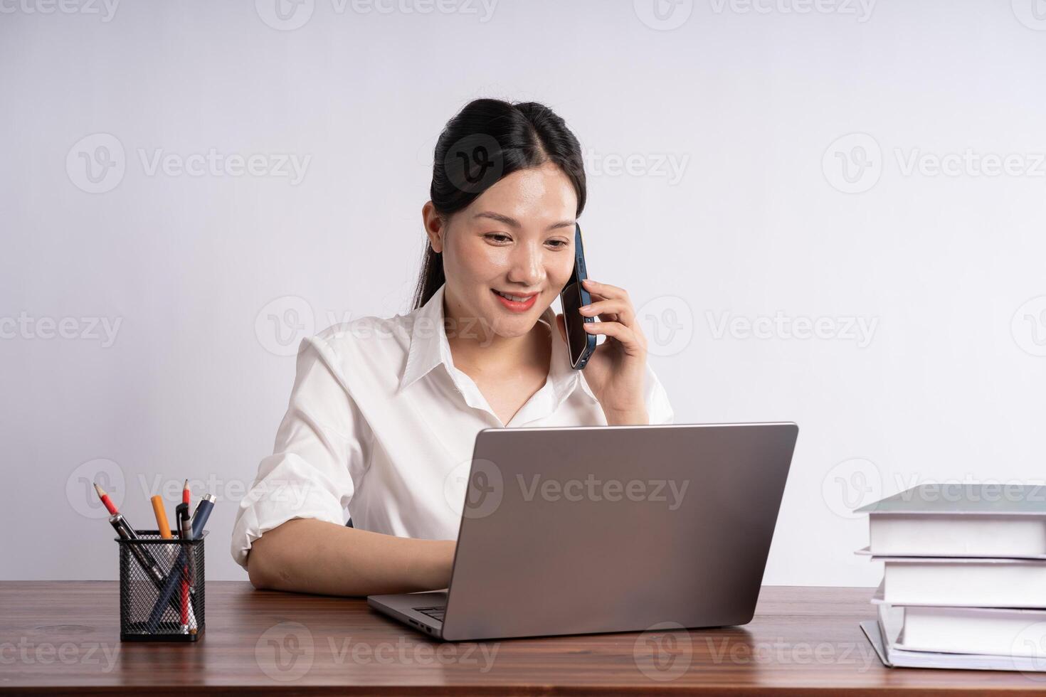 Young female businessman sitting at desk on white background photo