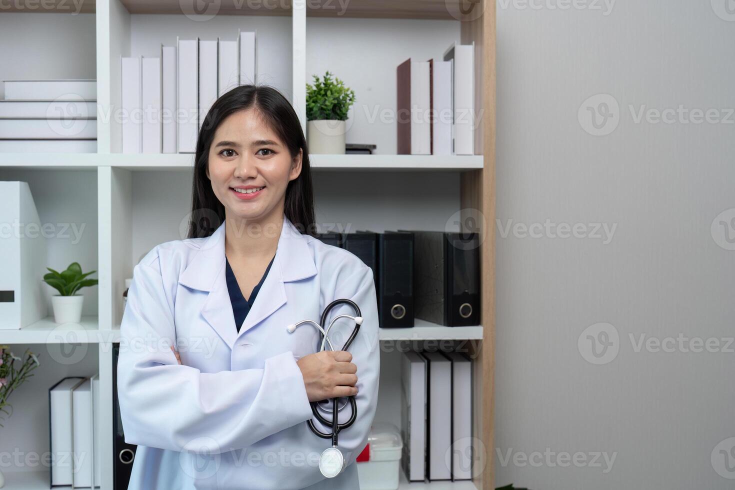 Confident Female Doctor in White Coat Holding Stethoscope in Modern Medical Office with Bookshelves photo