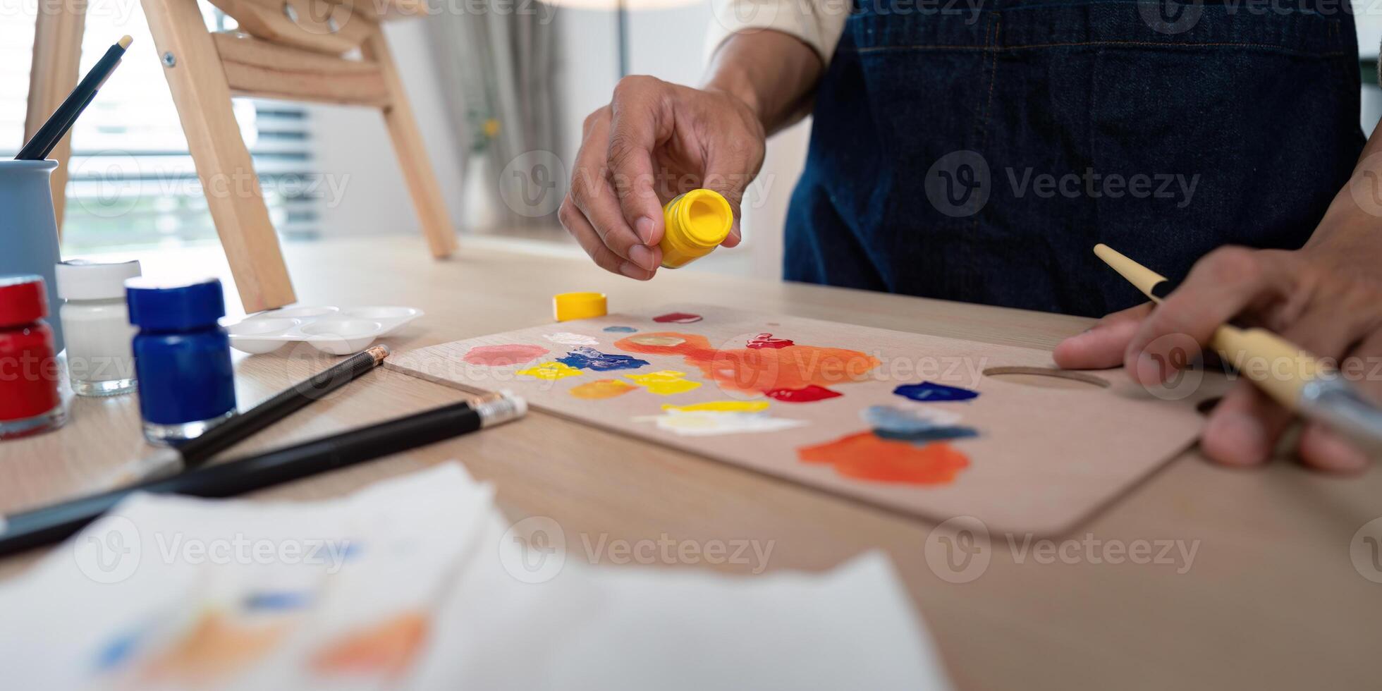 Artist Mixing Paints on Palette in Studio with Brushes and Easel in Background photo