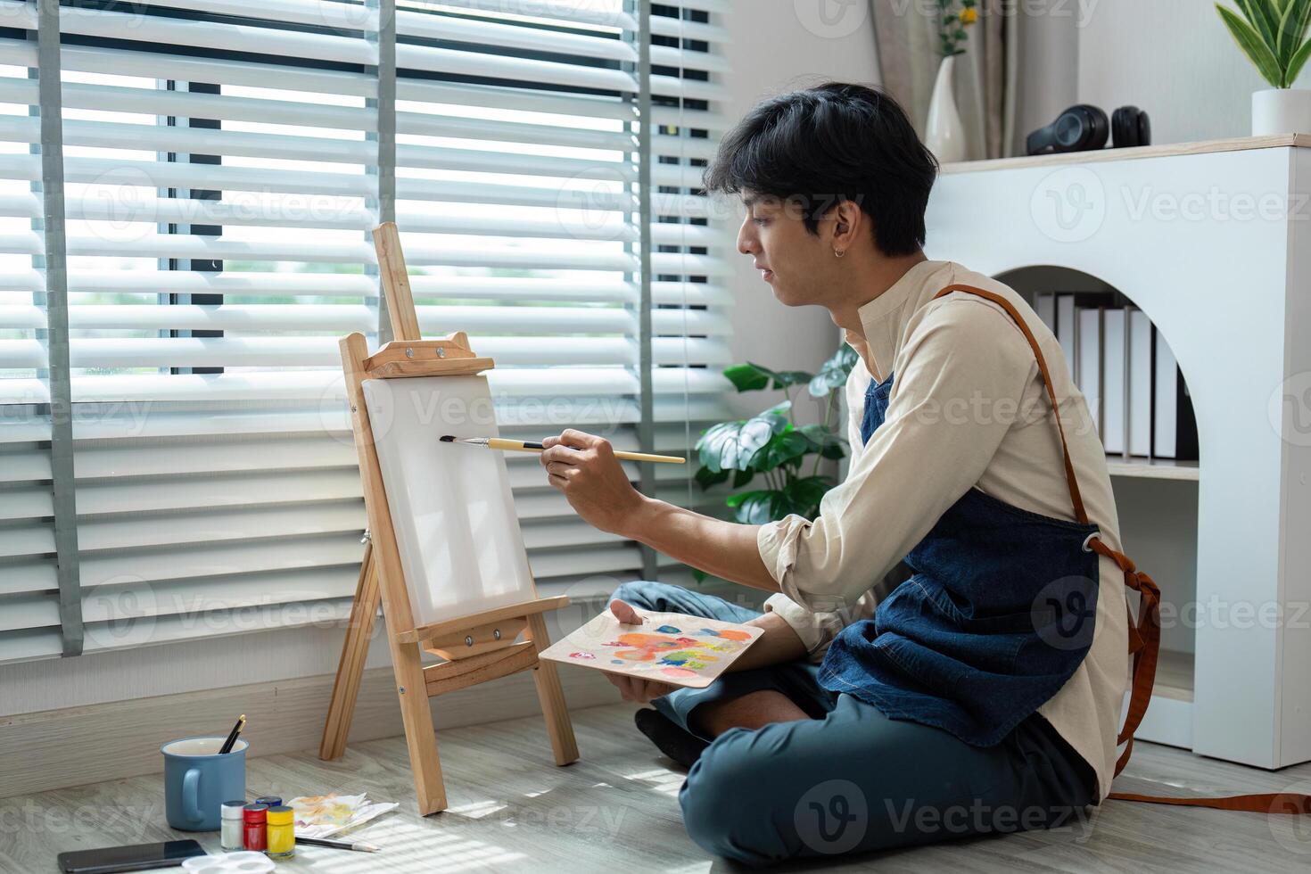 Young Artist Painting on Canvas in Modern Home Studio with Natural Light and Creative Atmosphere photo