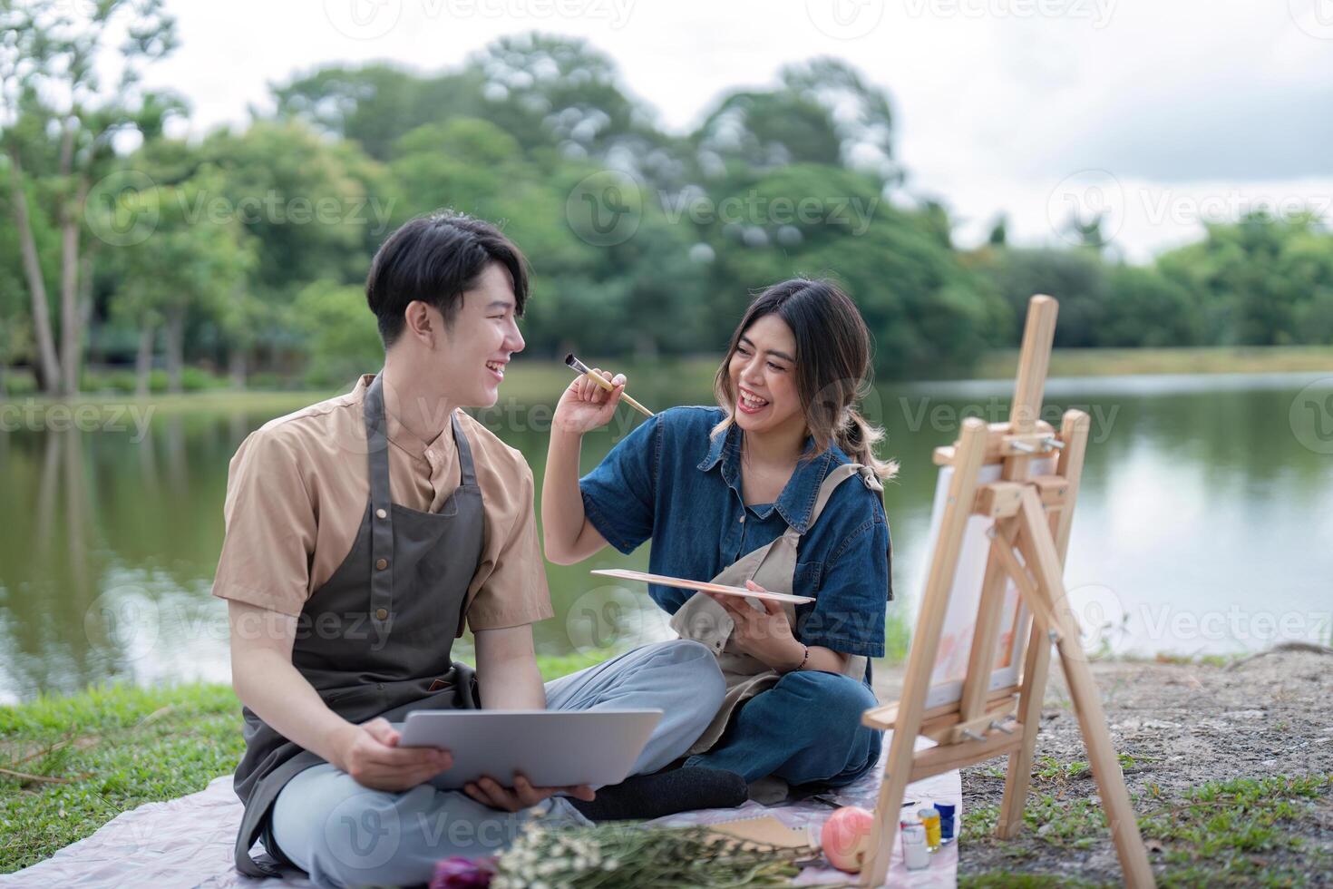 Romantic Couple Enjoying a Picnic by the Lake with Art Supplies and Nature in the Background photo