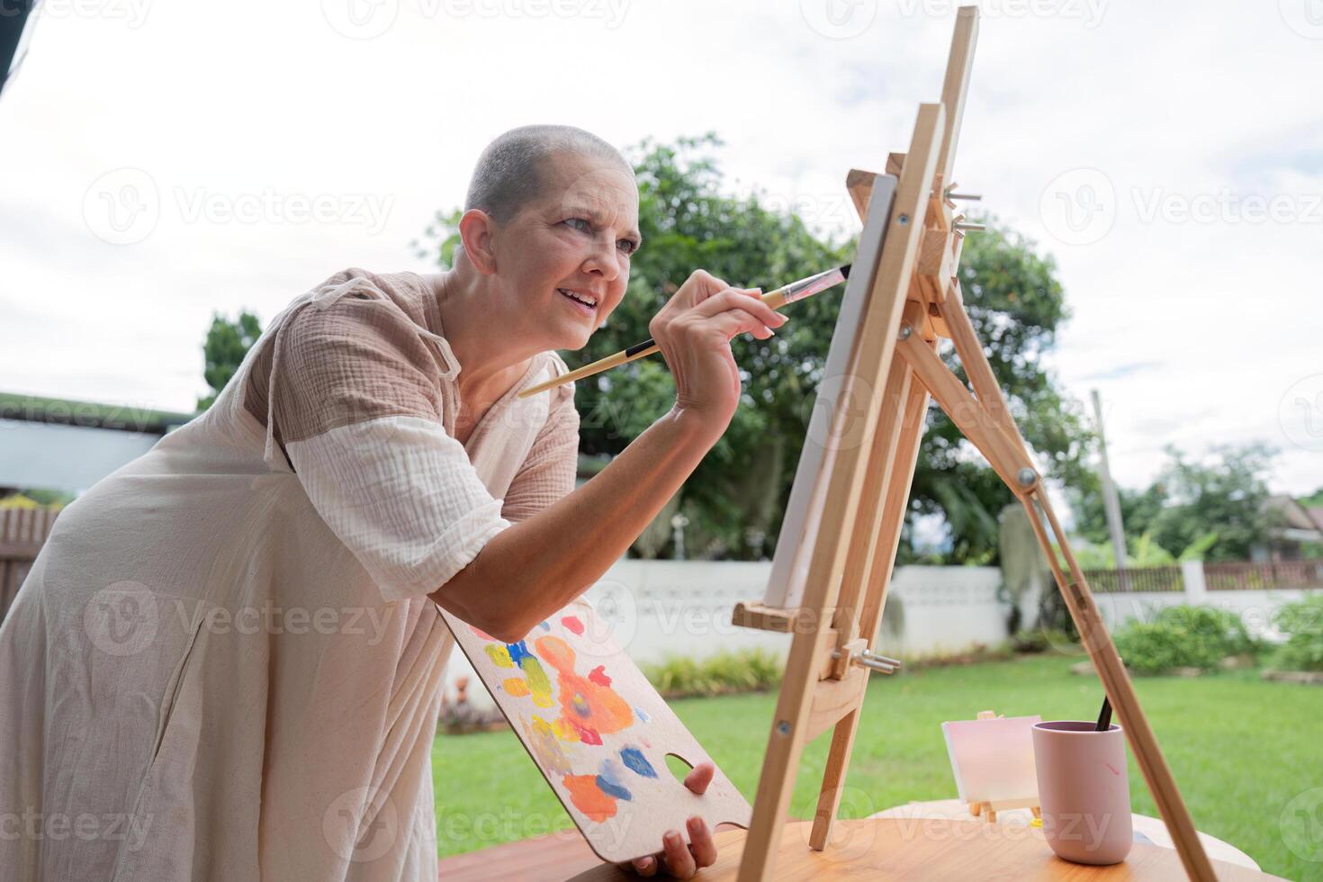 Woman Enjoying Outdoor Painting Session on a Sunny Day with Easel and Palette in a Garden Setting photo