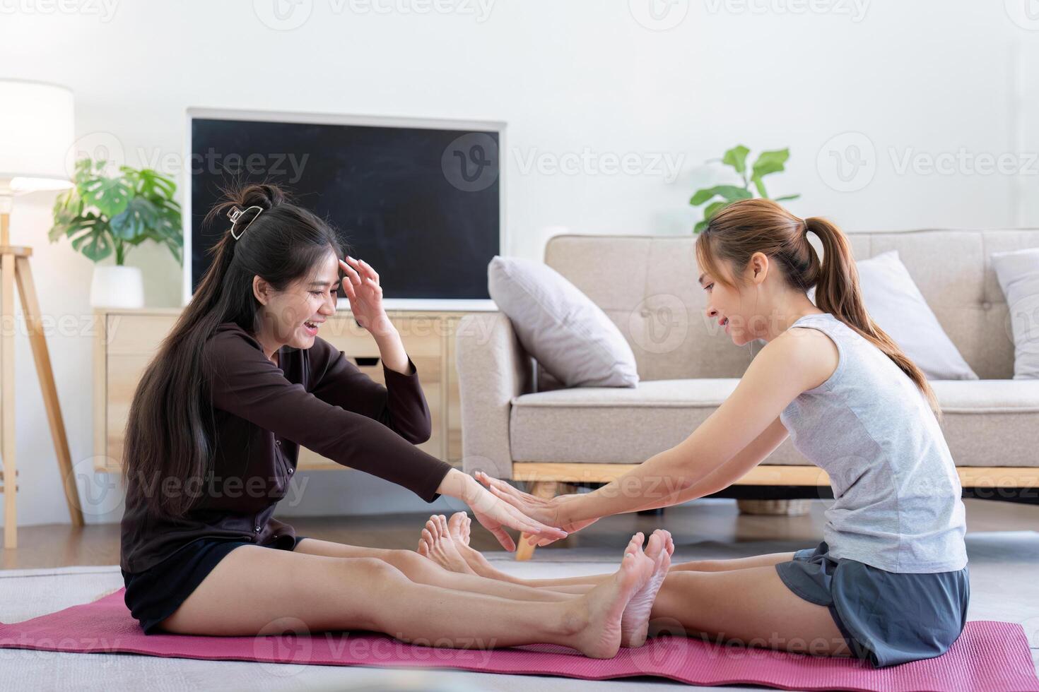 Two Happy Women Enjoying Yoga Together at Home. Lesbian Couple Bonding and Exercising on a Yoga Mat in a Cozy Living Room photo