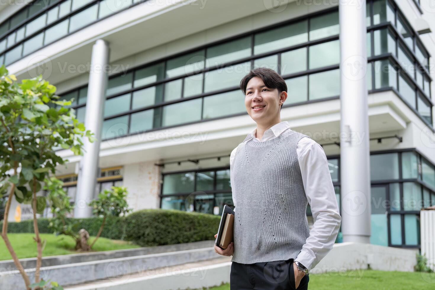 Young Professional Smiling Outside Modern Office Building Holding Notebook, Ready for Business Success photo